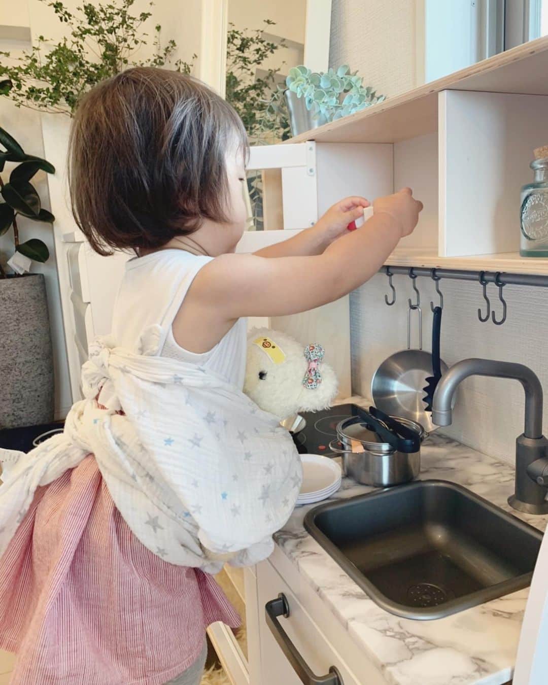 那須久美子のインスタグラム：「おはようございます☀️  赤ちゃん🧸を抱っこ紐で寝かしつけながら、せっせとご飯の準備🍴  まぁ忙しそうだこと💦  赤ちゃん🧸は頻繁にお熱出すし、怪我もするから絆創膏だらけ🤣💦  #2歳3ヶ月　#おままごと　#ママの真似っこ　#あるあるな光景　#クマさん　#クマさんは華の赤ちゃんです🧸　#朝の出来事　#元気に登園しました　#ママはお仕事がんばります！」