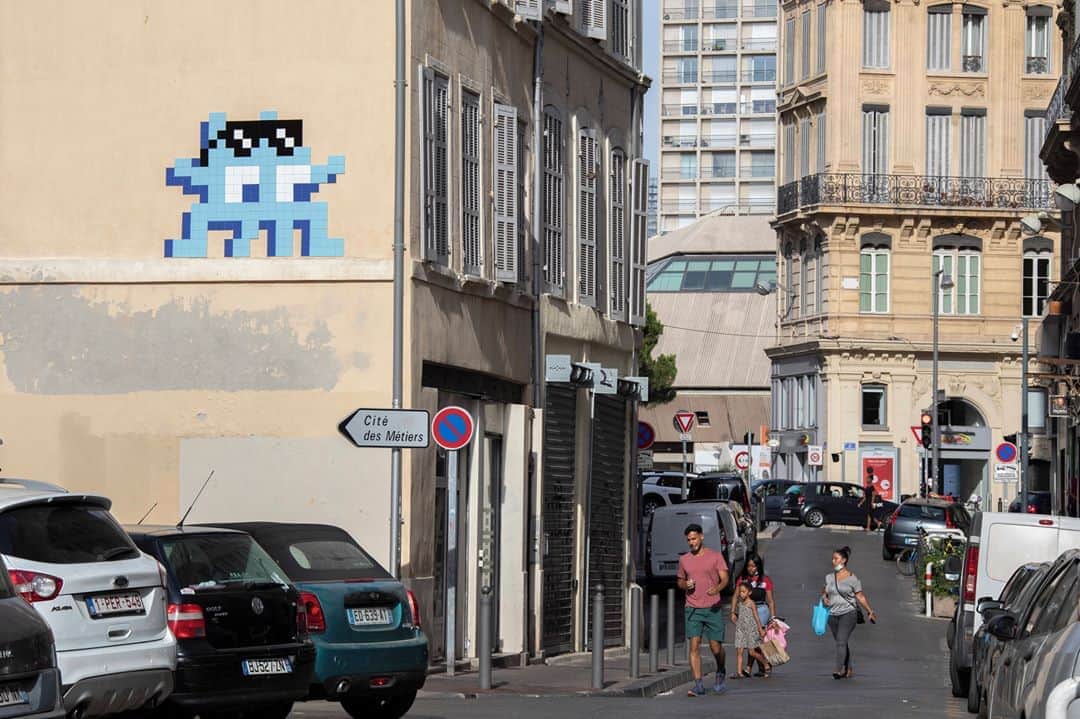 ルモンドさんのインスタグラム写真 - (ルモンドInstagram)「C’est une invasion éclair d’une ampleur inédite que les Marseillais et les vacanciers peuvent constater jour après jour depuis près de deux semaines. Invader est en ville, et inonde incognito, chaque nuit, les murs de space invaders, ses créatures en mosaïque à l’esthétique low tech, envahisseurs de l’espace urbain. Son QG, resté secret jusqu’au bout, surplombe la cité phocéenne : c’est le MAMO, le centre d’art que le designer Ora-ïto a ouvert en 2013 sur le toit-terrasse de la Cité radieuse de Le Corbusier.⁣ La voûte évasée formée par cet ancien gymnase donne à l’endroit une atmosphère de science-fiction, d’autant que le jeune quinquagénaire, qui tient à conserver son anonymat, a obturé toutes les vitres de papier kraft pour ne pas que les promeneurs voient ce qu’il s’y trame.⁣ ⁣ Invader est le huitième artiste invité de ses cartes blanches de l’été, après Xavier Veilhan, Daniel Buren, Dan Graham, Felice Varini, Jean-Pierre Raynaud, Olivier Mosset et Alex Israel. Chacun s’est confronté à la masse de béton et aux audaces modernistes du lieu.⁣ Jamais il n’avait posé autant de pièces en aussi peu de temps. Il en a envahi, pourtant, des villes, depuis la fin des années 1990 :  dont certaines plusieurs fois, et Paris en continu, avec plus de 3 950 pièces collées au total avec cette nouvelle vague marseillaise.⁣ « Habituellement, ça correspond à environ six mois de pose. Là, tout s’est fait en deux mois, c’est un petit coup de folie. J’ai l’impression de courir un marathon.»⁣ -⁣ 1 : Le street-artiste Invader en pleine préparation de son exposition-invasion, au MAMO, à Marseille, le 5 août.⁣ 2 : MARS_39, où l’on aperçoit un portrait de Zidane placardé façon affiche, à Marseille, le 9 août.⁣ 3 : MARS_56, dans le quartier du Vieux-Port, à Marseille, le 11 août.⁣ Photos : INVADER (@invaderwashere)⁣ -⁣ #culture #art #collage #invader #marseille」8月21日 21時15分 - lemondefr