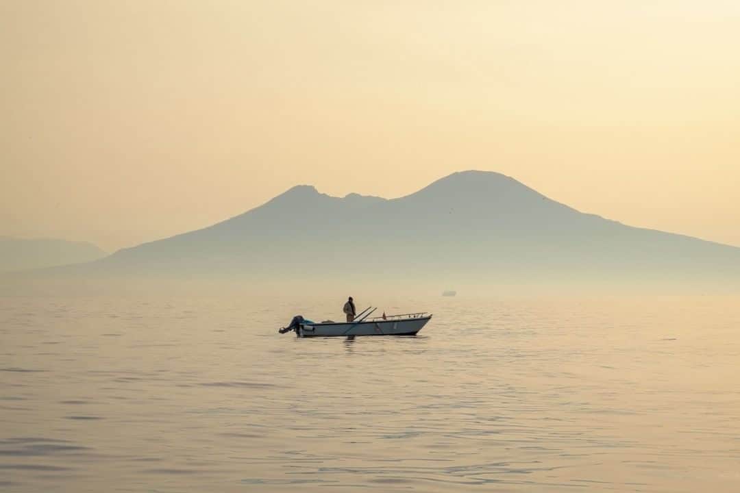 National Geographic Travelさんのインスタグラム写真 - (National Geographic TravelInstagram)「Photo by @francescolastrucci  A fisherman’s boat floats in front of the iconic silhouette of Mount Vesuvius at sunrise in the Bay of Naples, Italy. I boarded one of these small fishing boats before daylight, hoping I would get a different perspective of the bay and the surrounding landmarks. The fishermen, departing from the Port of Mergellina on their way to the spot where they placed nets the night before, crossed the bay at the precise moment when the first rays of the sun made their appearance. The warm gradient of the first daylight over the placid water made the environment almost ethereal.  Follow me @francescolastrucci for more places, daily life, and stories around the world. #italy #naples #dailylife」8月25日 9時05分 - natgeotravel