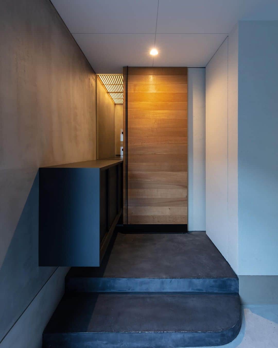 Horibe Associates co., ltd. さんのインスタグラム写真 - (Horibe Associates co., ltd. Instagram)「・ House in Higashisumiyoshi  more⇨@horibeassociates  玄関を抜けると 3層吹き抜けた明るいリビング空間が広がります。  そのため、前室である玄関は空間の対比として仕上げの明度を落とし、天井を低く抑えました。  玄関ドアはオーク板張りの引戸。既製品類が扉正面に現れないよう、鍵は枠のサイドに。  左の黒いボックスは内外連続した玄関収納。 外部の収納は傘掛けと宅配ボックス・郵便受けとなっています。  雛飾りを飾る予定の玄関収納の上部はお雛様を優しく灯す、行灯のような灯りをデザインしました。  3層吹抜けのリビング空間が家族を繋ぐ 木造３階建て中庭型住居  #耐震等級3 #長期優良住宅  photo @yoheisasakura ・ ・ #architecture#architect#architecturephoto#architecturephotografy #architettura#Kiếntrúc#arquitectura#Architektur#Arkitekture#architexture #マイホーム記録#マイホームメモ#ガレージハウス」8月26日 20時21分 - horibeassociates