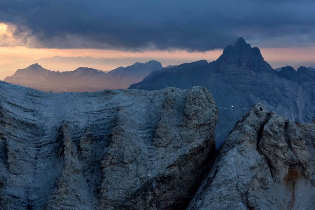 National Geographic Travelさんのインスタグラム写真 - (National Geographic TravelInstagram)「Photo by Robbie Shone @shonephoto  Mountains always remind us how small we really are, never more so than in the Dolomites. Climbers and mountaineers are always chasing that perfect blue sky, but the Dolomites often look their best with some clouds breaking up the panorama, especially when the sun is rapidly disappearing. As the peaks in the distance begin to recede into darkness and the shafts of light become even thinner and weaker, the already extraordinary ambience of this fascinating and beautiful place becomes, for a fleeting moment, even more haunting.   Here the longest suspension bridge in the Dolomites is seen in the final moments of daylight. The Ivano Dibona via ferrata is a restored historical route, which was used by Italian troops during World War I.」9月11日 17時08分 - natgeotravel