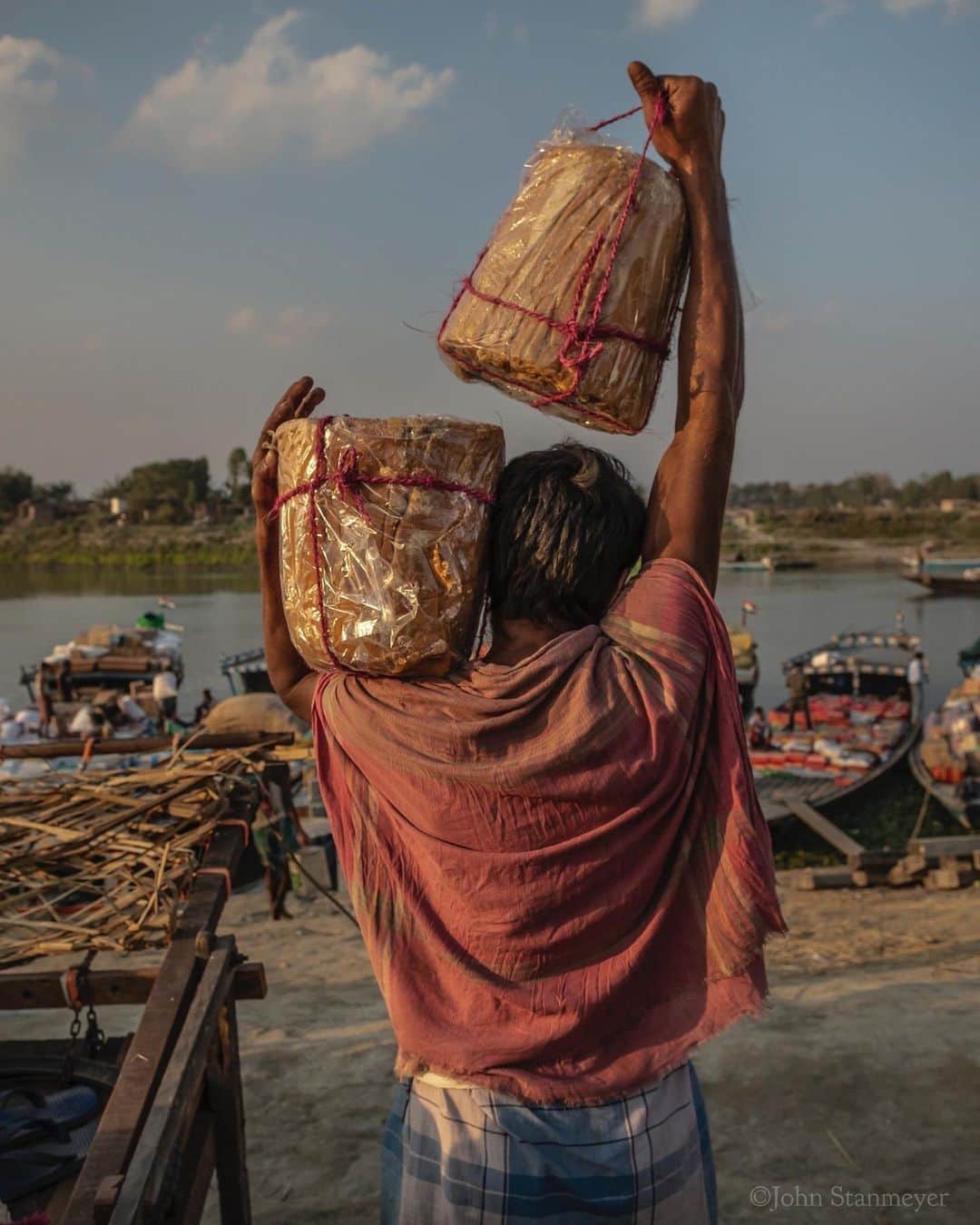 のインスタグラム：「There was something about the fading crimson red cloth, how it draped his shoulders and back as a worn movie theater curtain. How many 11 kilos (25 pounds) chunks of jaggery had been rested upon the fabric, crushing his burdensome shoulders to protect his skin? All-day till night, this man and an ensemble of others make a living carrying supplies from the shore in Dhubri, India, to boats that transport items like these conical bricks of sugar, cooking oil, stoves, furniture, items sometimes unimaginable, to remote villages along the Brahmaputra River. Rarely did these men rest during the three hours I stayed with them. I could understand…having carried only two bricks of jaggery from his cart to the boat, without such a beautiful sash, I would prefer moving unceasingly than to rest. Avoiding the body of knowing what abuse it was receiving. ⠀⠀⠀⠀⠀⠀⠀ India’s Daunting Challenge: There’s Water Everywhere, And Nowhere - Chapter 8 of the @outofedenwalk, my latest story in the August 2020 issue of @natgeo magazine. ⠀⠀⠀⠀⠀⠀⠀ #india #assam #dhubri #jaggery #sugar #hardlabor @natgeo @outofedenwalk #walkingindia #edenwalk」