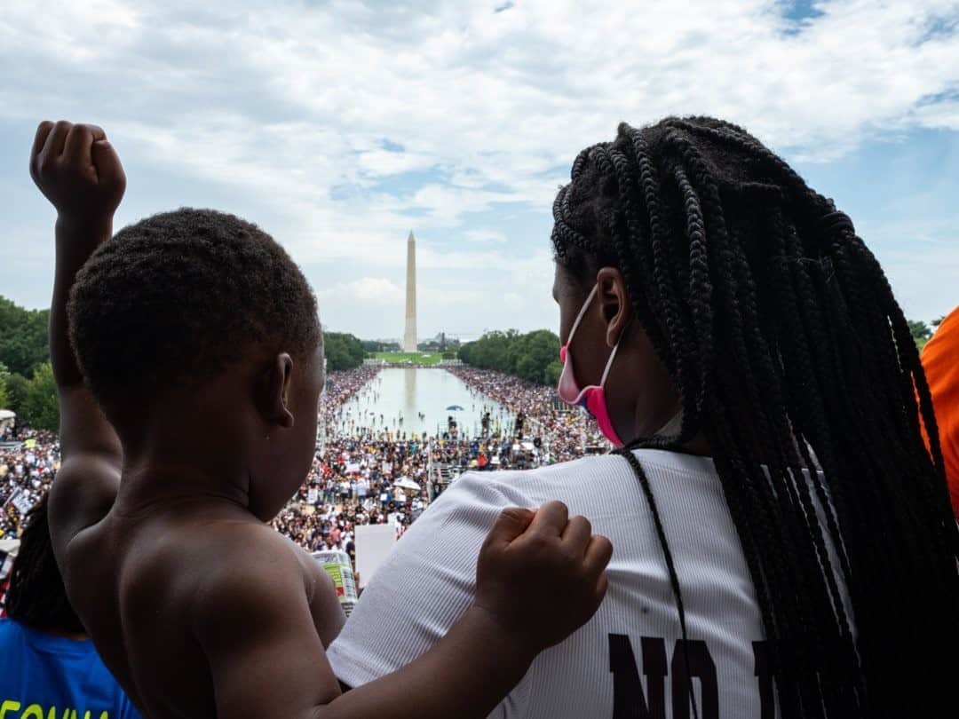 のインスタグラム：「Photo by Joshua Rashaad McFadden @joshua_rashaad  Alena Battle held her child at the Commitment March in Washington, D.C., yesterday. People from across the country gathered in protest of police brutality. The Commitment March honored the 57th anniversary of the March on Washington for Jobs and Freedom, which occurred on August 28, 1963, and emphasized the work still to be done, especially on police and criminal justice reform.」