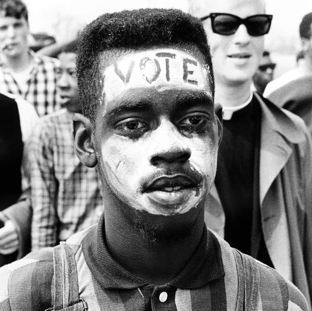 マックスウェルさんのインスタグラム写真 - (マックスウェルInstagram)「V O T E 📧 • 🦅• 🗳• ✊🏿 ✊🏾✊🏽✊🏼  “the definition of insanity is doing the same thing and expecting another outcome “  we can’t afford this insanity   📸 : @brucedavidsonphoto   🗓 : SPRING OF 1965  Somewhere between Selma and Montgomery, in the first days of spring 1965, Bruce Davidson took a photograph of a young black marcher. The young man’s name is not recorded, but he appears in several of Davidson’s photographs of the march from Selma to Alabama’s capital. It’s no mystery why. The young man’s painted face illustrates the fight for voting rights in literal, stark relief: “VOTE.” The word is his skin, his blackness. Whiteness, in the photo and in the United States, is required for both the word’s legibility and the citizenship it represents.  📱: @plus1vote • 👈🏾」9月1日 0時58分 - maxwell