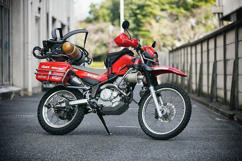 ヤマハ バイクさんのインスタグラム写真 - (ヤマハ バイクInstagram)「👨‍🚒人命救助のためのスーパーセロー👩‍🚒  東京消防庁には人命救助や消火活動を行うための二輪車部隊が配備されている。ヤマハ・セロー250をベースにした消防活動二輪車、通称「クイック・アタッカー」である。  クイック・アタッカー隊が創設されたのは1997年のこと。95年に発生し、各地に甚大な被害をもたらした阪神淡路大震災の教訓からである。地震によって建物が崩壊すると瓦礫などが散乱して道路をふさぎ、車だけでは充分な対応ができなくなるからだ。  隊員には普通自動二輪免許でもなれるが、学科と実技の厳しい試験をクリアし、約3週間の実技研修を受ける必要がある。実技試験では一本橋やスラローム、8の字走行といった基本的なことを実車で行う。研修ではいわゆるオフロードライディング的な訓練もあるが、装備があるのであまりアクロバティックなことはしない。安全確実に現場へ向かうことが大事だからだ。また、出動も安全上の観点から日の出から日没までと決まっている。  人命救助という崇高な目的のために少しずつ距離を刻むクイック・アタッカー。その存在はセロー250に乗るすべてのオーナーに誇りを与えてくれるのではないだろうか。  #防災ライダー #防災の日 #セローはいいぞ #スーパーセロー #クイックアタッカー #serow250 #セロー250 #yamahaserow #yamahaserow250 #YAMAHAが美しい #東京消防庁 #消防活動二輪車   ⭐︎プロフィール欄のリンク先から「クイック・アタッカー」についての記事を読めます！」9月1日 20時19分 - yamaha_bike