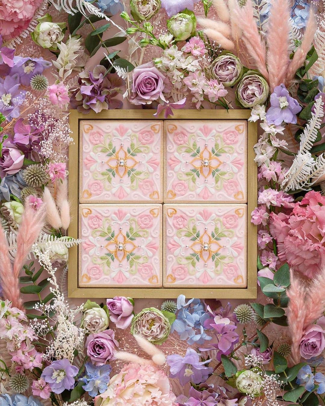 KUNIKAのインスタグラム：「Flower Garden Cookie Tile -Sunset Pink-﻿ ﻿ せっかくタイルを作るなら、どんな柄にしよう...作りたいデザインがありすぎる...そんな中でやはりこれだ！となったのは、大好きなお花をちりばめたシンメトリーデザインでした。❃﻿ ポルトガルやモロッコなど、様々な国の本場のタイルに影響を受け魅了されましたが、どこの国のタイルにも似つかない、オリジナルを作れたらと思い誕生したデザインです。﻿ ﻿ アイシングのぷっくりした線や絞り、レースのようなテクスチャー、立体的なお花、アクセントにアラザン。﻿ アイシングクッキーならではのデザインを沢山取り入れました。﻿ ﻿ プリントしたら平面になってしまうけど...クッキーのように割れやすくもなく、生活の一部に飾ったり、使っていただけるセラミックタイル。﻿ 日常に必要不可欠でもなんでもない不思議なアイテムですが、そこが気に入っています🥰﻿ ﻿ 発売は今夜、9月4日(金)21:00〜オンラインショップにて。﻿ ▶︎https://kunika.theshop.jp﻿ ﻿ ※フレームは別売りになります。﻿ ﻿ ❃Special thanks❃﻿ Flower artist : YUKI @plus_flower_2020 ﻿ ﻿ #artofkunika」