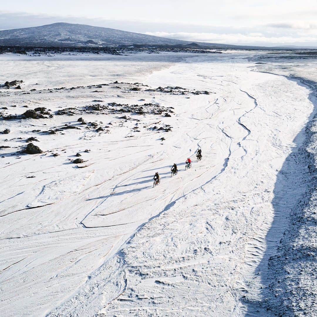 クリス・バーカードのインスタグラム：「When we left the aptly named “Star Wars Hut” on day 3 of the Iceland Traverse we woke up to clear but freezing conditions. Frost was covering everything including the bikes & a thin layer of snow had drifted in overnight. The day proved to be sunny & warm but this goes to show how quickly a forecast can change. The freezing temps were in fact just what we needed to cross the rivers safely. The water levels had lowered significantly from the record breaking 25°C temps the week before when we deemed it impassible on the scout.  This photo captures on of my favorite memories. Riding across a dry and frozen riverbed, still full of beautiful textures. Trying to navigate as best we can and follow fading tire tracks.   📷 @jordanrosenphotography」