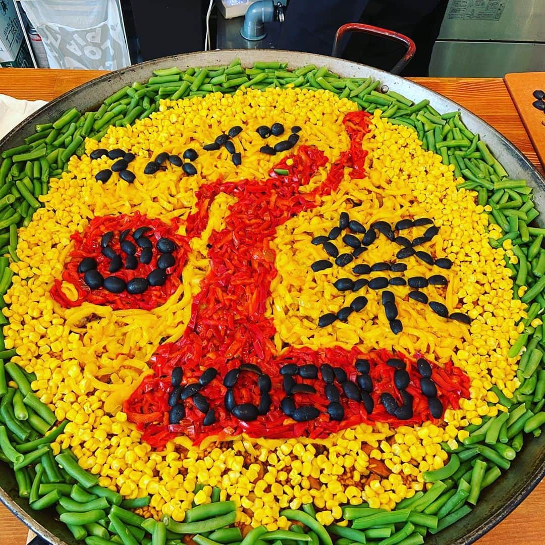 カワハラユキコのインスタグラム：「【デコパエリア！/Decoration paella】 🇪🇸 きのう、無事にスペイン祭のメインイベント、ギャラリーでの個展とスペインマルシェが終了しました👏👏👏👏 ・ 魚介のデコパエリアはこんなかんじで制作。私の考えた図案をもとに @eltragon.tranomon の栗原シェフが材料を用意してくれて(着色料とかなしの自然食材です。赤はパプリカ、黄色はコーンとパプリカ、黒は黒オリーブ)、それを小杉湯となりの器用軍団(吉田さん&はとちゃん)の助けを借りて仕上げました。温泉マークも入ってるよ！ ・ でも実は最初、シェフからデコパエリアを提案されたときは、ただの食いしん坊の私は、(おいしければ、飾りとかどうでもいいけどな)とそんなに乗り気じゃなかったのです。でも、小杉湯となりで意見聞いたら見たい人多数でやることにしたら、当日は大盛り上がり。みんな写真撮って撮影して発信するからパエリア販売の宣伝になるし(実際、瞬殺で売り切れました)、私も想像以上に楽しいし、祭がパッと華やかになったし、イベントの仕組みの勉強になったなあ。 ・ ただいま、日本パエリア協会youtube(Japan paella asociacionでyoutubeでググってね)で録画配信中です。よかったらみてみてね！ 🇪🇸 【オラ！スペインごはん祭」in 主に高円寺】 ・ ⭐︎9/4～10/18 ミニ個展「オラ！スペイン温泉」 ＠「小杉湯」玄関ギャラリー(小杉湯営業時間:平日15時30分〜深夜1時45分、土日は朝8時〜深夜1時45分、木曜定休) ・ そのほかのイベントは終了しました。 ・ 書籍とスペイン手ぬぐいをご購入いただいた方には、主に高円寺の協賛スペイン料理店をおトクに楽しめる「スペインチケット」をプレゼント中です(書籍事前購入の方も対象です。上記の書籍販売箇所でその旨おしらせください)。関係各所で配っている「スペインMAP」を手にお楽しみください。Vamos！ 🇪🇸 #オラスペイン旅ごはん #スペインごはん祭 #スペイン  #スペイン料理  #スペイン旅行  #スペイン語  #食べ物グラム #spain #foodie #食いしん坊 #スペインごはん #高円寺 #高円寺グルメ #パエリア #デコパエリア #銭湯 #小杉湯となり #paella」