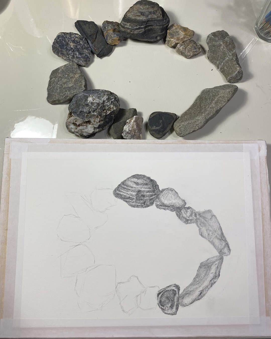 SUGAYA MASAKI / SHIMAさんのインスタグラム写真 - (SUGAYA MASAKI / SHIMAInstagram)「さて、第二課題。 // "石を円環に置きdessinする" 今回は石で円環をつくり、それをdessinするとゆうシンプルな課題です。  -Drawing process- 教室から5分程、渓流へ降りて行き、気になった石を15個程拾って、それを綺麗に磨いた。 そして机の上で石の円環を作る。初めに先生から、石を円環に置くことで円の向こう側があるような事を感じて置き、描いてみましょう。と、お話がありました。  初めに渡されたのは2H〜2Bまでの鉛筆と練り消し、それ以外は何も無く、どおぞご自由にと。ーー  まずは石を眺める。フォーカスを絞る、石の色味、凹凸、模様に次々と気付き、石ひとつ一つの個性が自分の中で生まれる。 今ある装備の全てを知恵に変え、鉛筆を色々な角度で紙に当て塗ってみたり、練り消しをアレやコレやと形を変形させて使う、塗った部分を指でなぞり、影を柔らかくしたりした。線を描かずに石のカタチを描きたいと思った。 ー 1日目, 6つの石を描いたところで終了。 ここまで描いてみて、まぁ悪くない。ただ考え、思うところは私が描いたdessinは、紙の上に描かれた石。ただ石を紙に描いたとゆうだけだった。 集中ーーー🧘🏻‍♂️ #描く集中の記録#Drawing#dessin#my#masakisugaya」10月5日 18時43分 - masaki_sugaya