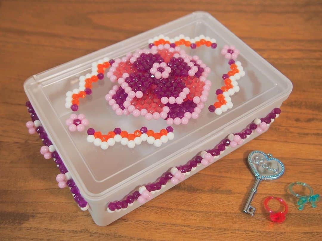 のインスタグラム：「アクアビーズで小物入れをデコってみました✨ 100円ショップなどで売っているシンプルなケースも、カラフルなアクアビーズで飾ればあっという間にオリジナル小物入れに。 . 大きめのモチーフを付けるだけでなく、小さなパーツ・ライン状のパーツなどをいくつか作ってレイアウトすると、バランスよく仕上がりますよ😊 . ●水にぬれる恐れのあるものには付けないようにしてください。 ●大切なものへのデコは、保護者の方と相談してから行いましょう。 . #アクアビーズ #aquabeads #ビーズ #beads #アクアビーズアレンジ #ハンドメイド #デコレーション #小物入れ」