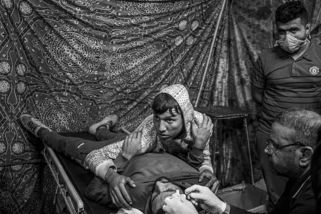 のインスタグラム：「Photo by @moisessaman  On February 2, an injured Iraqi protestor with a birdshot bullet wound to his forehead is comforted by another protestor at a makeshift first aid station near Al-Khilani Square in Baghdad. The ongoing series of youth-led protests, calling for the end of the sectarian political system that has existed in Iraq since the U.S. invasion, started in October 2019 and continue to this day.」