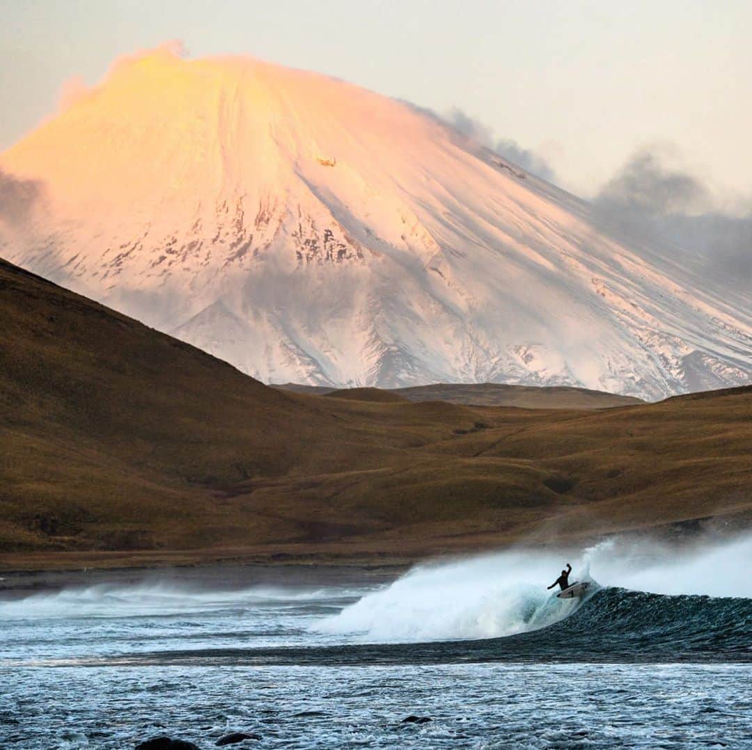 クリス・バーカードのインスタグラム：「I remember this session almost didn’t happen. I didn’t take much , but a little coercion was needed. The Volcano convincing me mostly. It was our longest day out yet and the temps were dropping fast into the sunset hour. We knew one more session after a marathon surf would result in a windy, dark and cold ride home on a sketchy track that often got us stuck. The guys were sun & wind beaten and ready to head back. As soon as we came around the corner I could see the clouds beginning to part around the volcano and decided to give it one more check. I knew the moment the rim started to show I was staying there till dark even if to shoot empty waves. Luckily the crew was an enticed as I was and the daunting task of getting into a wet 6mm wetsuit began. Tired limbs & beat red faces moved through the surf like molasses for this final hour of sunset. All our necks felt the strain from staring up at the volcano.  .  I shot this on an unconventional lens. I was using the 100-400 where I would have normally used the 70-200 ... but I realized that extra compression was just what It needed. This is my favorite image that published in the recent @surfersjournal of the trip. @parkercoffin @roark  @benweiland @natezoller @harrisonsan @_ryanhill_」