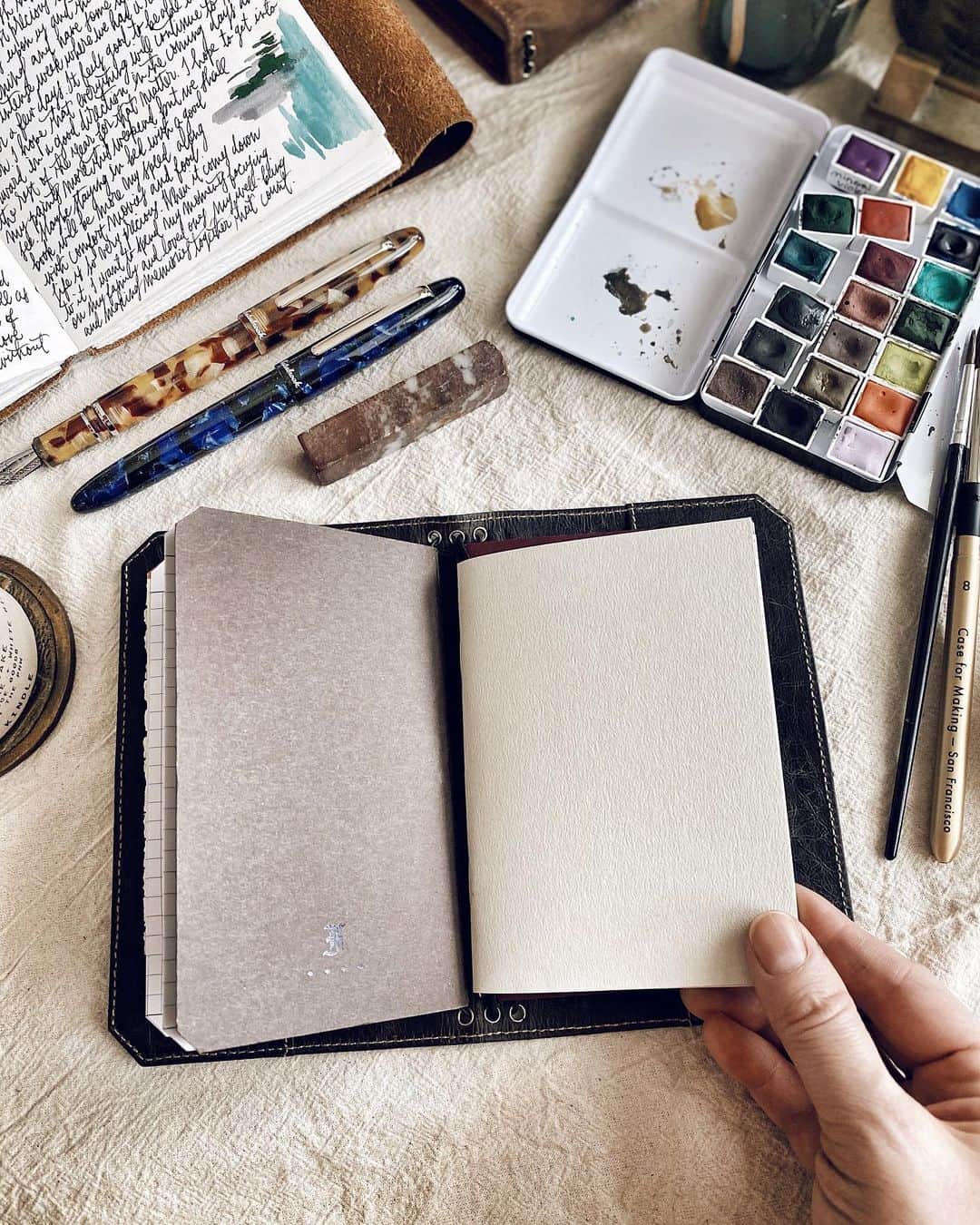 Catharine Mi-Sookさんのインスタグラム写真 - (Catharine Mi-SookInstagram)「Savouring the tiny bits of time where I can write and paint. Life brings unexpected rhythms, a theme this year, and so we adjust and attune ourselves accordingly. I’ve been holding my VN Pocket close lately as it’s the perfect size for the little bursts of creativity and musings. Today I painted this simple landscape and it was wonderful to be able to slow down, even if just for a few minutes here and there. I hope each of you are finding pockets of rest and refuel throughout your days too with silver linings and goodness laced in all the details. ✨ . . . Vagabond Pocket in NWF Dark Brown co-designed by @franklinchristoph & myself — link in bio. . Watercolors @caseformaking. Estie Fountain Pens @esterbrook_official. Leather Journal @quillandarrow. Penvelope Three Case in NWF Dark Denim @franklinchristoph. . . . #journaling #dailyjournal #vagabondpocket #franklinchristoph #vagabondnotebook #caseformaking #handmadewatercolors #abmcrafty #esterbrook #esterbrookpens #esterbrookestie #fountainpens #watercolorlandscape #watercolours #fountainpenaddict #stationerylove #travelersnotebook #flatlaystyle #passporttravelersnotebook #thedailywriting #penmanship #journalinspiration #journallove #artjournalpages #artjournaling」9月17日 4時02分 - catharinemisook