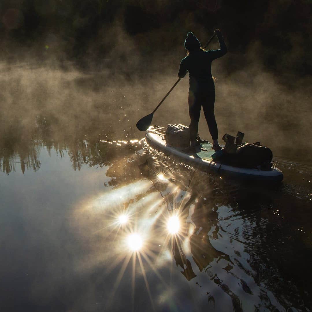 Tim Lamanさんのインスタグラム写真 - (Tim LamanInstagram)「Photos by @TimLaman.  Multiple sun reflections off the ripples in the glass smooth water of the Moose River create a surreal scene as my daughter Jessica paddles through the mist of the chilly morning.  Shot last weekend during our three-day, 40+ mile paddleboard adventure on the Moose River in Western Maine.  Second shot shows the full height crop of the image, which includes a cool sunburst at the top, but also a lot of lens artifacts above Jessica.  I decided I liked the tighter crop of the first shot better but thought I’d also share the wider shot.  Which do you prefer?  I’m curious because in video, people seem to love lens flare and sun artifacts in the lens, but in stills, usually not.  The key photo tip here when shooting into the sun is just don’t worry about it, shoot and see what you get.  I never anticipated getting four sun reflections at once!   #SUP #Maine #Paddleboarding #mist #supexpedition #TL_WildlifePhotoTips」9月17日 11時45分 - timlaman