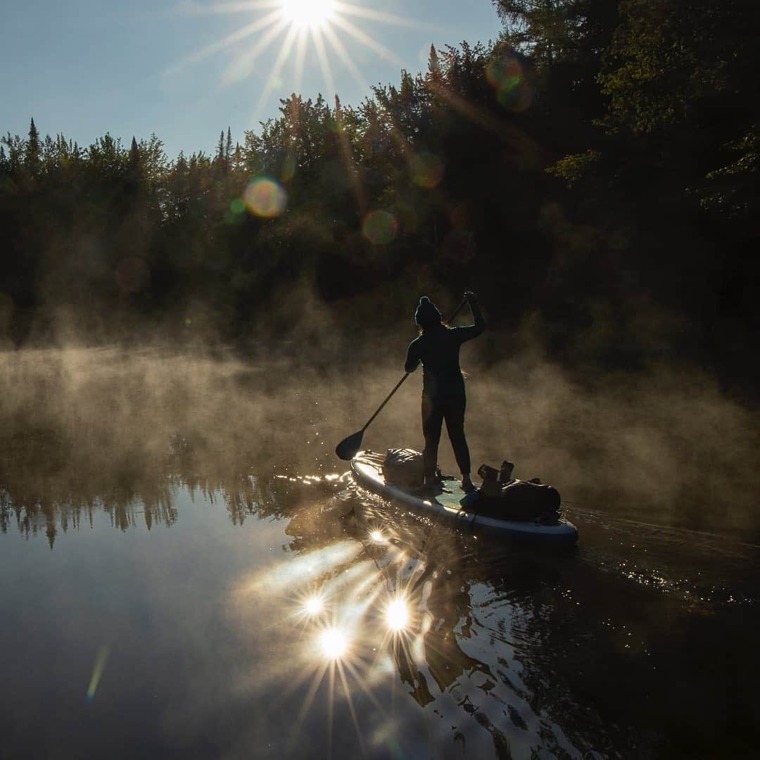 Tim Lamanさんのインスタグラム写真 - (Tim LamanInstagram)「Photos by @TimLaman.  Multiple sun reflections off the ripples in the glass smooth water of the Moose River create a surreal scene as my daughter Jessica paddles through the mist of the chilly morning.  Shot last weekend during our three-day, 40+ mile paddleboard adventure on the Moose River in Western Maine.  Second shot shows the full height crop of the image, which includes a cool sunburst at the top, but also a lot of lens artifacts above Jessica.  I decided I liked the tighter crop of the first shot better but thought I’d also share the wider shot.  Which do you prefer?  I’m curious because in video, people seem to love lens flare and sun artifacts in the lens, but in stills, usually not.  The key photo tip here when shooting into the sun is just don’t worry about it, shoot and see what you get.  I never anticipated getting four sun reflections at once!   #SUP #Maine #Paddleboarding #mist #supexpedition #TL_WildlifePhotoTips」9月17日 11時45分 - timlaman