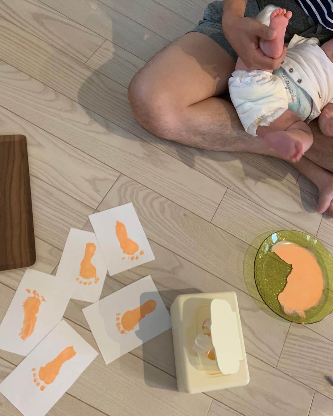 糸数美樹のインスタグラム：「明日の敬老の日の準備✋🦶 . . . 子供の手形とるの大変すぎてびびったけど、足は意外と楽チン。 赤ちゃんに使っても大丈夫な絵具ないかな？って、ネットでいろいろ調べてたらちゃんとしっかり洗えば市販の水彩絵の具でも大丈夫みたい🙆‍♀️ ってことで、DAISOでペールオレンジを購入。 真ん中には娘の写真を入れる予定！ 喜んでくれるといいなぁ〜 . . . 今回学んだこと👏 1.手は寝てる時がやりやすい 2.爪は先に切っておく 3.足は寝てる時よりは起きてる時のほうが取りやすい 4.終わったらすぐお風呂に入れられるように準備しておく✍️ . . . これできっと次やるときはスムーズにいくかな笑。まーまーてんやわんやでした🤦‍♀️  p.sパンパースうすまさおしっこしてるのは見逃してーーー！笑」