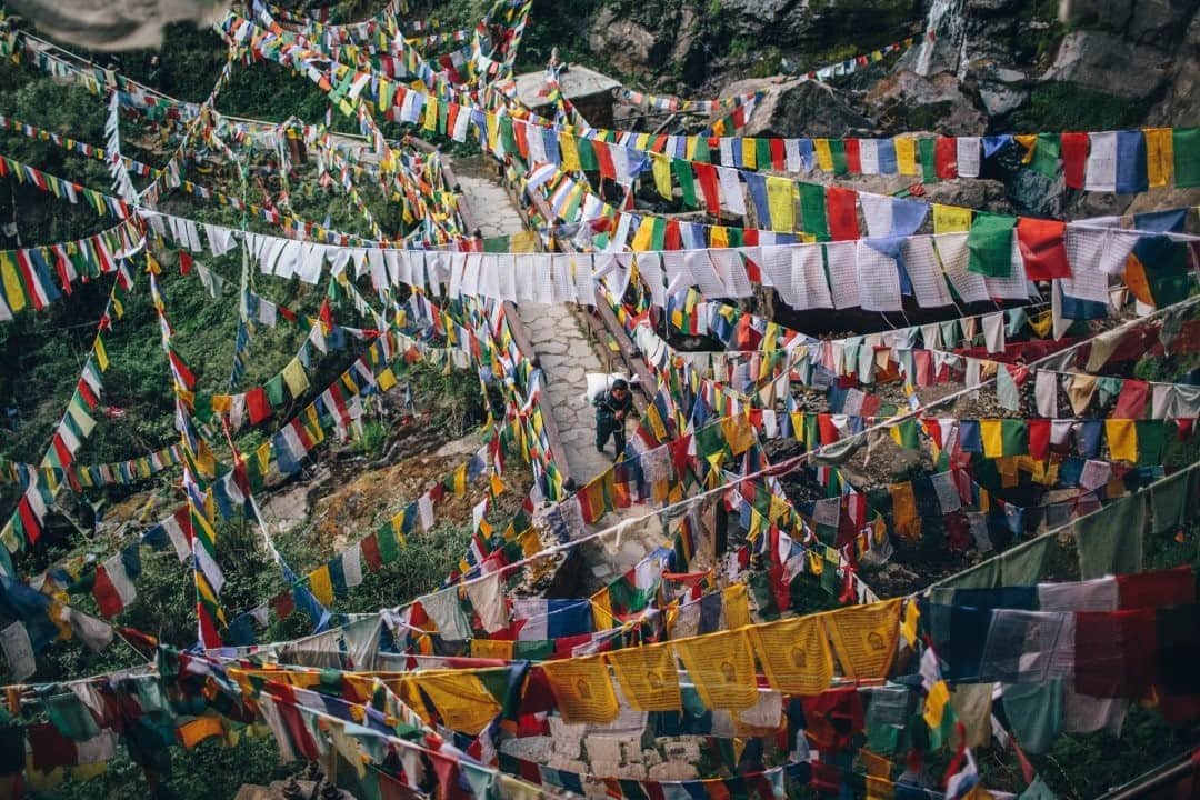National Geographic Travelさんのインスタグラム写真 - (National Geographic TravelInstagram)「Photo by @joshuacogan / Thousands of prayer flags surround a porter as he carries a load over the final bridge to the Tiger's Nest temple in Bhutan. The nearly four-mile-long (six-kilometer-long) trail to the temple can only be traveled by foot, as there are no roads to the temple. As a result, everything at the temple is brought by hand.  For more pilgrimages around the world, follow me @joshuacogan. #Bhutan #Buddhism」9月24日 21時08分 - natgeotravel