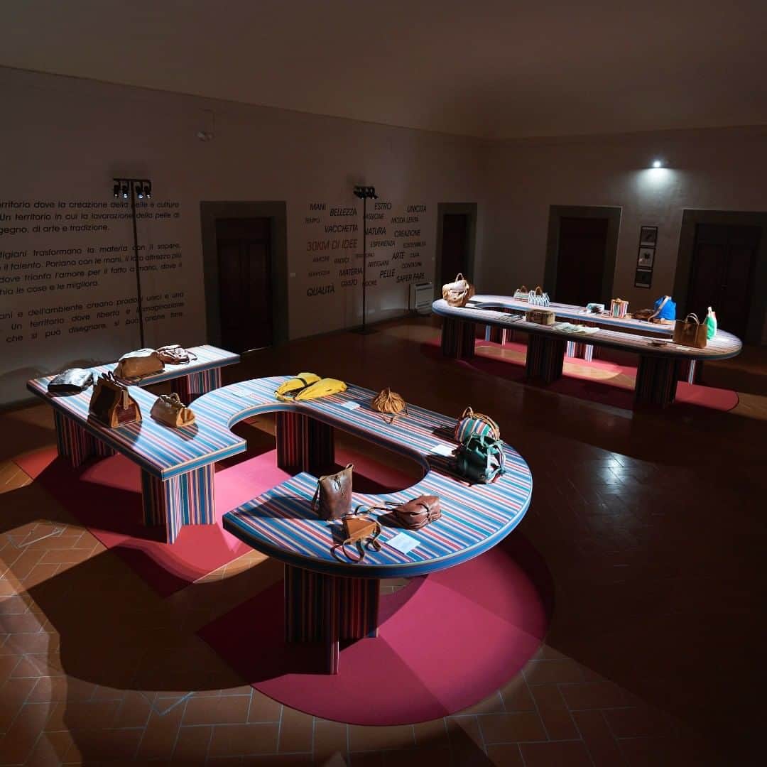 のインスタグラム：「Celebrating our 50th anniversary with the evocative #installation by @felicelimosani.  Iconic 'deckchair' striped canvas covers two tables that retrace Il Bisonte's history through the most significant bags in our historical archive.  From the 1970s to our most recent creations it's been a journey that testifies to a lasting Made-in-Italy love story. ☆ #ilbisonte #leathergoods #leatheraccessories  #craftmanship #installation #madeinitaly」