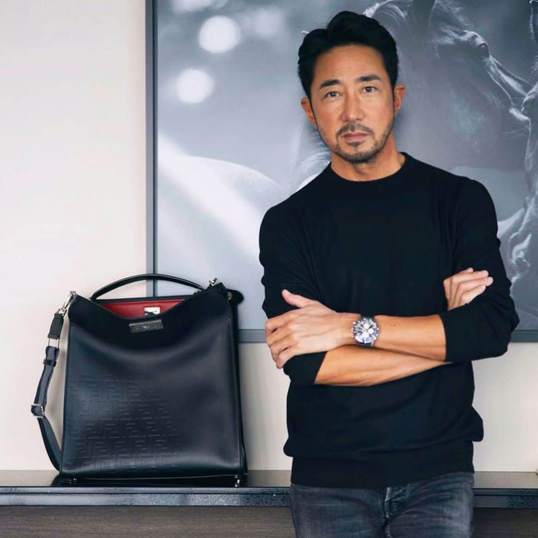 のインスタグラム：「【多面的な表情のおすすめバッグ‼️】1925年にイタリアの皮革製品店として創業された「FENDI（フェンディ）」。ラグジュアリーブランド唯一の自社ファーアトリエも持っているレザーグッズの名門として知られています。そんなFENDIの中でも、アイコンバッグとして人気なのが「ピーカブー」。「いないいない、ばぁ！」という意味の通り、バッグの口を開けた時の素材や色の切り返しが特徴で、このデザインはクリエイティブディレクターのシルヴィア・フェンディさんがお孫さんをあやしている時にインスピレーションを得て誕生しました。 ____________________________________________________________ 中でも気に入っているのが写真の「ピーカブーエックスライトフィット」。何が良いって、最近スーツ以外のカジュアルなモノトーンのスタイルが増えたんですが……。そんな時に持つと、単なるシンプルなスタイルに終わらず、適度にモード感を演出してくれるわけ。パッと見は黒なんですけどね。バッグの口を開けた時にチラッと赤が覗くのもいいんです。単なる黒のカーフに見えて、実はさりげなくFFロゴがエンボス加工されているんです。しかもグラデーションで。職人が一点一点、斜めにしながらエンボス加工を施しているという懲りようなんです。ハンドル持ちだけでなく、ショルダー使いもできるから本当に便利で。使い方次第で、二面どころか、多面的な魅力があるのがいいんですよね。ということで、間もなくFORZAでも動画を近日公開予定。その動画の内容がマジでヤバイ。ここでは言えませんがお楽しみに！  @fendi  #fendi #fendipeekaboo @yoshimasa_hoshiba  #yoshimasahoshiba  #干場義雅 @forzastylecom  #forzastyle」