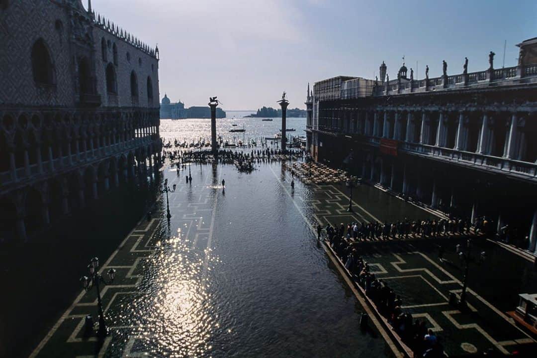National Geographic Travelさんのインスタグラム写真 - (National Geographic TravelInstagram)「Photos by Michael Yamashita @yamashitaphoto / End of fall flooding? / Fall marks the beginning of the acqua alta, or high water, season in Venice, Italy. It’s the period when high tides flood the city’s canals and piazzas and tourists scurry to find knee-high boots. The phenomenon has occurred for centuries, but a rise in sea level and a drop in land level—due to natural and man-made problems including climate change and industrialization—have produced dramatic increases in the amount and frequency of flooding. In November 2019, the city was inundated with the highest water levels in 50 years, leaving ground floors of many buildings uninhabitable. The floods have driven many of the 50,000 residents away from the city, surrendering it to the annual (pre-pandemic) influx of over 30 million tourists.  A search for a solution to keep Venice above water has been on for decades. Finally, after delays and cost overruns, an ambitious project begun in 2003 had its first successful test this month. The MOSE (Modulo Sperimentale Elettromeccanico) project, which consists of a series of 78 mobile gates, was activated and succeeded in blocking high tides of over four feet (1.2 meters) from entering the Venetian Lagoon. The entire endeavor is not expected to be fully completed until 2021, but officials and residents of the city are hopeful that it will be enough to keep Venice a vital city—and not merely a waterlogged museum. #venice #acquaalta #sanmarcosquare #piazzasanmarco #yamashitaphoto」10月27日 23時42分 - natgeotravel