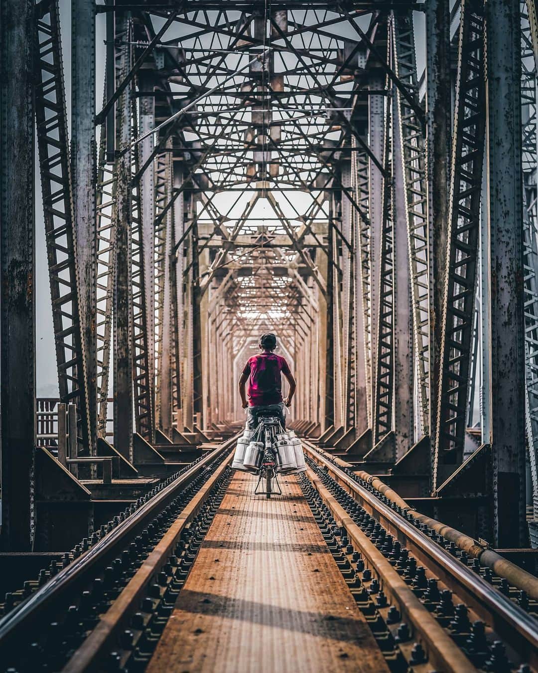 Canon Asiaのインスタグラム：「Here's what we call an excellent portrayal of architectural framing by @__swap__! 😍  The repetitive pattern on the trestle bridge along with the railway track gives this shot a centralised and well-balanced composition. Additionally, the natural vignette effect from the backlight and monotonous support structure lead the viewer to the main subject seamlessly.  The railway bridge crossing is a must for many on their way to wok daily, and this photo captures determination despite a journey of hardship.  📷 Image by @__swap__ using the Canon EOS 77D • EF50mm f/1.8 STM • f/2.8 • ISO 100 • 1/640s • 50mm  Got a shot with a story to tell? Tag us #canonasia or share them on My Canon Story, link in bio!  #canonasia #photography #explore #composition #colours #canon #symmetry #lens #inspiration #train #railway #subject #architecture #architecturephotography #colours #leadinglines #dombivli」