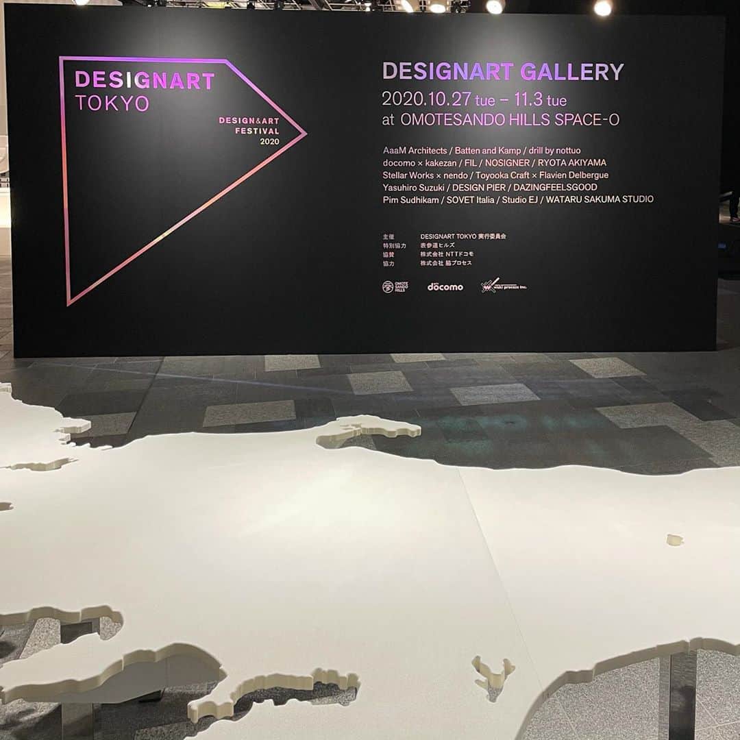 林信行のインスタグラム：「11月3日（火／文化の日）まで、都内66の会場（＋オンライン）で「DESIGNART TOKYO」が開催している。  DESIGNART : the annual collection of design x art events are taking place in 66 venues throughout tokyo. DESIGNART Gallery in OmotesandoHills would be a good place to start.  66の会場すべてを回るのはかなり大変だが、仕事の帰りの気分転換に寄れる夜19時や20時頃までオープンしている会場も多い。 最初に訪れるなら、注目の大型展示が集積している大型会場がオススメだ。 特に表参道ヒルズ地下３階、スペースOの「DESIGNART GALLERY」はアクセスが良いだけでなく、名前の立ったクリエイターのアート作品、課題解決型デザインの提案、家具／インテリア、伝統工芸の技、さらには5G通信やドローンを使ったテクノロジーの提案とDESIGNARTの面白さの幅のすべてが凝縮されている。 　階段を降りてくると巨大な楽譜が見えてくるが、これはNOSIGNER（太刀川英輔さん）による憂鬱なソーシャルディスタンスを楽しく変えるデザインの提案で、音符の上に立つとサティの曲からとった音が鳴る。楽譜の先には彼がコロナ禍で行った情報支援 #PANDAID を紹介するパネルも置かれている。 　入り口の開口部を埋めるように広がるのはアーティスト #鈴木康広 さんによる巨大で精密な日本地図。実際の日本列島と向きを合わせており、能登半島の辺りに腰掛けて「日本海はこっち側か」と思いを馳せてみたり、なだらかな曲線に地球の丸みを感じ取ったりできる。 　そのすぐ裏にある巨大ドームはNTTドコモによるもので5G通信とドローンを使った空飛ぶディスプレイの提案。球体にドローンが収まっていて、空を飛べるだけでなく、そこに遠隔地にいる人の顔が映し出される、というもので、ライブ会場などでの演出に使うと楽そうだ。 　反対側には人気デザイナーnendoが手掛けたSTELLAR WORKSの家具や、日本の工芸とデンマークデザインを学んだフラヴィアン・デルベルグが豊岡クラフトのためにつくったモジュール化された天竜産ヒノキを使ったモジュール卓上小物「Hako Collection」が展示されている。 　個人的には左奥にあった一連のインテリアの展示が物凄くよかった。DESIGNPIERによるキュレーションで床から斜めに伸びた筒のようなもの、これはStudio EJによるテーブルで、実は中に水平なガラス面がある。 　日本を代表するプロダクトデザイナー100人にも選出されている岩崎一郎さんがつくったイスもシンプルで美しい。 　他にもRYOTA AKIYAMAさんによるペットボトルなどの人工物を再加工してつくったインテリアや、AaaN Architectsによるタバコの箱を再利用する提案など、説明を聞いて改めて驚く作品の展示も多い。  初めてDESIGNARTを見る人は、ここで自分の関心の磁力がどっちの方面に向いているのかを探ってみるのも良いかもしれない。  なお、この会場のプレスツアーの様子をPerisciopeで中継した記録がこちらに残っているので会場の雰囲気をつかみたい人は見てみて欲しい： https://www.pscp.tv/w/cmjMSTU3M3wxQlJKall3UnBRcEd3aUghrRzXmB3aGRvJN4L3htlyxmjFze_CgThGsk1OIQM=  #DESIGNARTgallery #SpaceO #OmotesandoHills B3F -11/3 11-20  #DESIGNART #鈴木康広 #YasuhiroSuzuki #太刀川英輔 #NOSIGNER #nendo #StellarWorks  #FlavianDelbergue #岩崎一郎 #IchiroIwasaki et al.  #designarttokyo2020report」