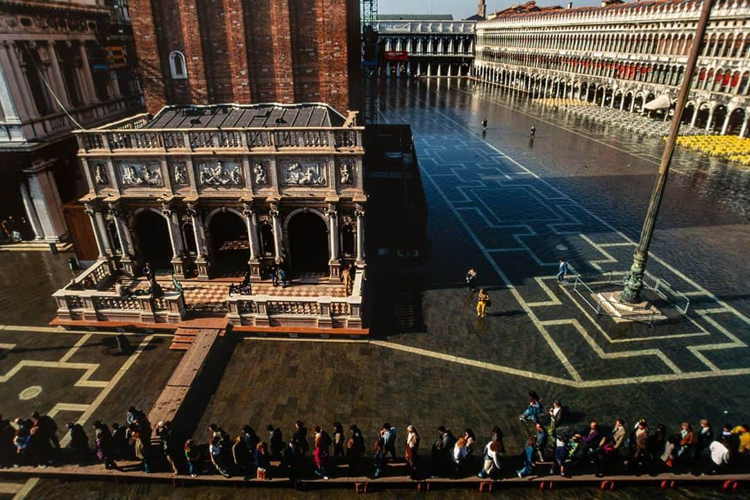 Michael Yamashitaさんのインスタグラム写真 - (Michael YamashitaInstagram)「End of fall flooding? Fall marks the beginning of the Acqua Alta, or High Water, season in Venice, Italy. it’s the period when high tides flood the city’s canals and piazzas and tourists scurry to find knee-high boots. The phenomenon has occurred for centuries, but a rise in sea level and a drop in land level – due to natural and man-made problems including climate change and industrialization – have produced dramatic increases in the amount and frequency of flooding. In November 2019, the city was inundated with the highest water levels in 50 years that left ground floors of many buildings uninhabitable. The floods have driven many of the only 50,000 residents away from the city, surrendering it to the annual (pre-Covid) influx of over 30 million tourists.    A search for a solution to keep Venice above water has been on for decades, but finally, an ambitious project begun in 2003 finally – after delays and cost overruns -- had its first successful test this month.  The MOSE (Modulo Sperimentale Elettromeccanico) project, which consists of a series of 78 mobile gates, was activated and succeeded in blocking high tides of over four feet from entering the Venetian lagoon. The entire endeavor is not expected to be fully completed until 2021, but officials and residents of the city are hopeful that it will be enough to keep Venice a vital city, and not merely a water-logged museum. #venice #acquaalta #sanmarcosquare #piazzasanmarco #yamashitaphoto」10月7日 6時45分 - yamashitaphoto