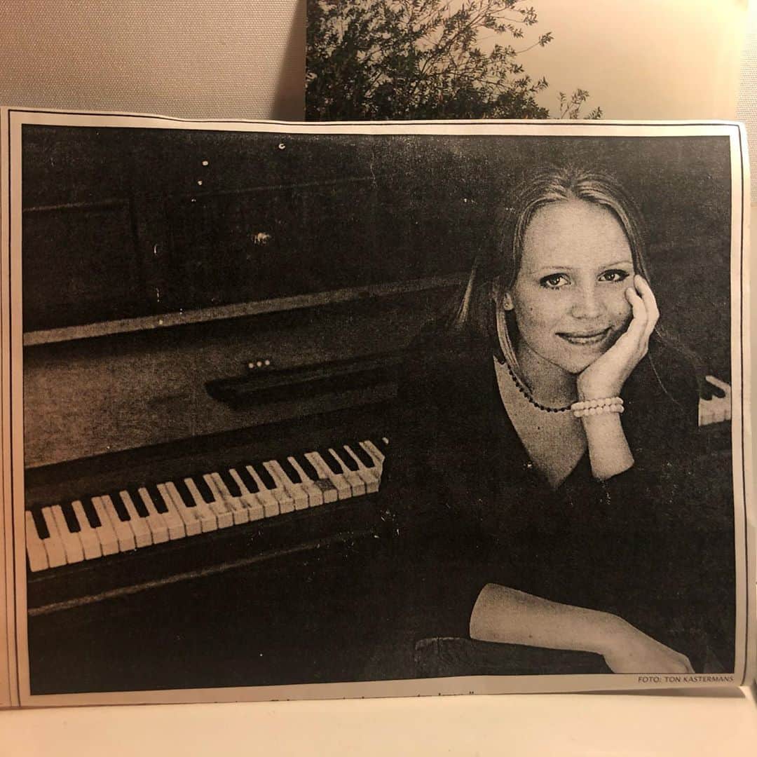 ヤナ・スクラのインスタグラム：「Foto in de krant, 18 jaar (wenkbrauwen bestonden toen nog niet). Ik had de Kunstbende gewonnen, althans, de voorronde en ik mocht als klap op de vuurpijl een liedje zingen in de pauze van een door tientallen mensen bezochte Spoken Word avond in de bovenzaal van Paradiso... Het minibeetje zelfvertrouwen om die dingen überhaupt te doen kwam door Judith, muzieklerares op de Huizermaat (middelbare school in Huizen). Die had namelijk een keer gezegd dat ik een mooie stem had... en door Aïsha (laatste foto) mijn klasgenoot met wie ik een paar maanden het duo Silver&Gloom vormde. Die sowieso alles durfde zodat ik een beetje in haar schaduw kon oefenen. Het moet ergens beginnen... #meermuziekindeklas ✨ Ik wil er trouwens van maken #meerkunstindeklas... (❤️ voor Tekenlerares Joslène) want ook als je bijvoorbeeld al jaren op de zuid-as geld aan t harken bent, kun je misschien nog met weemoed terugkijken op het momentje dat je een vogel tekende en weg vloog. p.s. viool werd m duidelijk niet」