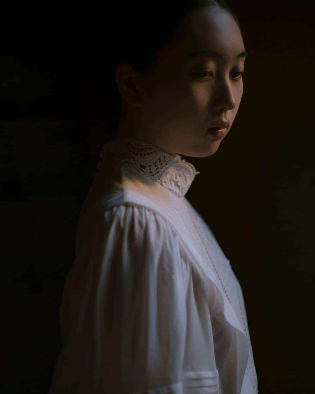 The Fashion Postさんのインスタグラム写真 - (The Fashion PostInstagram)「#portraits Maiko Kurogouchi  『「窓にカーテンを選ぶように、生地を選びました」 黒河内真衣子』  ― 昔のカーテンを思い出す質感、柄。いろんなディテールが表現されているのに気づきます。  カーテンの独特の艶を表現したいと思って、断面が角ばったナイロンの糸をシルクに混ぜてみました。偏光するので光が当たった時に水面のように輝いて、柄が浮かび上がるんです。昔の磨りガラスで見かけたような柄のニットもあります。これは靴下を編むようなハイゲージの機械で編むことで、繊細な表現ができています。  カーテンが風を孕んで膨らむようなシルエットを出したセットアップは、遮光カーテンをイメージして作りました。シルクノイルのような節感をポリエステルで表現しているので、光沢がありながらイージーケアなんです。軽くて着やすい感じも、現代の遮光カーテンぽいかなと。あと、カーテンと花瓶がある窓枠のシーンをそのままデザインした服もあります。花は、自粛期間中に自分の家に飾っていたアヤメやユリの花を図案化しています。Mame でよく使う植物や自然のモチーフは、いつも旅先でサンプリングしているのですが、今回は、自宅での生花が中心です。枯れた花、押し花にした花、生花のスケッチなどが、ダイレクトに洋服になっています。  ― キーカラーは、やっぱり白でしょうか。コンセプトムービーも、白いヴェールをかけたようなトーンが印象的でした。  記憶を思い出す時に浮かぶシーンって、なんだか白いなと思ったのがはじまり。そして必ずしも美しい映像ばかりではない。哀愁だったり、不安な感覚だったり。そういう感情のレイヤーと、カーテンのヴェールを潜っていくような、不思議な感覚を重ねた映像にしようということになりました。  今回、映像は奥山由之さんに監督を依頼しました。8mmのフィルムカメラで撮った 5:4 の比率のままなんですが、実はスマホでいつも見ている画角に近かったりして。むしろ今の視聴スタイルにマッチしているよね、という面白さもあります。  ― ヴィジュアルも世界観を優先した、ポエティックな48枚のシリーズ。  ランウェイではできない、デジタルだからこそ伝わるものをやろうと想いました。ヴィジュアルは野田祐一郎さんにお願いして、場所は、自分のホームグラウンドである長野を選びました。窓とドレスの組み合わせを決めるのが、無限のパズルのピースを合わせていくような作業で、ものすごい時間がかかりましたが、信頼する仲間たちととことん突き詰めて撮影することができたのは、本当に久しぶりでよかった。窓の前にいたり、窓から入る自然光を捉えたり。すべての写真に少しずつ、窓の要素が入っています。  Yoshiyuki Okuyama 📷 Yuichiro Noda  interview & text: Miwa Goroku  #TFP #TheFashionPost #MameKurogouchi #Mame #マメ #MaikoKurogouchi #黒河内真衣子 #21SS #奥山由之 #YoshiyukiOkuyama #YuichiroNoda #野田祐一郎」10月8日 17時37分 - tfpjp
