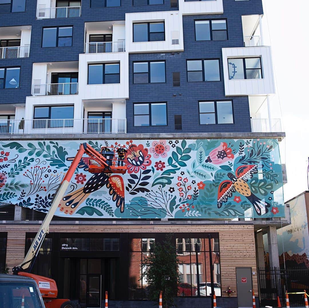 Dinara Mirtalipovaのインスタグラム：「Today was an exciting day to witness the process of installation of my long awaited mural! I designed it for Cleveland’s new residential complex called @livechurchandstate that is located right in the intersection of the historical Church Ave and old State st ( now West 29th). It’s my first public art project and I was so excited and optimistic about it and yet so worried and obsessed over every little detail. We arrived around noon and the crew was already in the process of hanging the top side. It’s printed on a mash breathable material and is expected to last a few years. There’s a total of 8 façades and they will be hung in the next few days. I’ll definitely stop by to see it all installed and will give you a tour.  👉P.s. head over to my IGTV there’s a longer video of us being excited 😊🌿 #mirdinaraxchurchstate #thisiscle  @thisiscle」