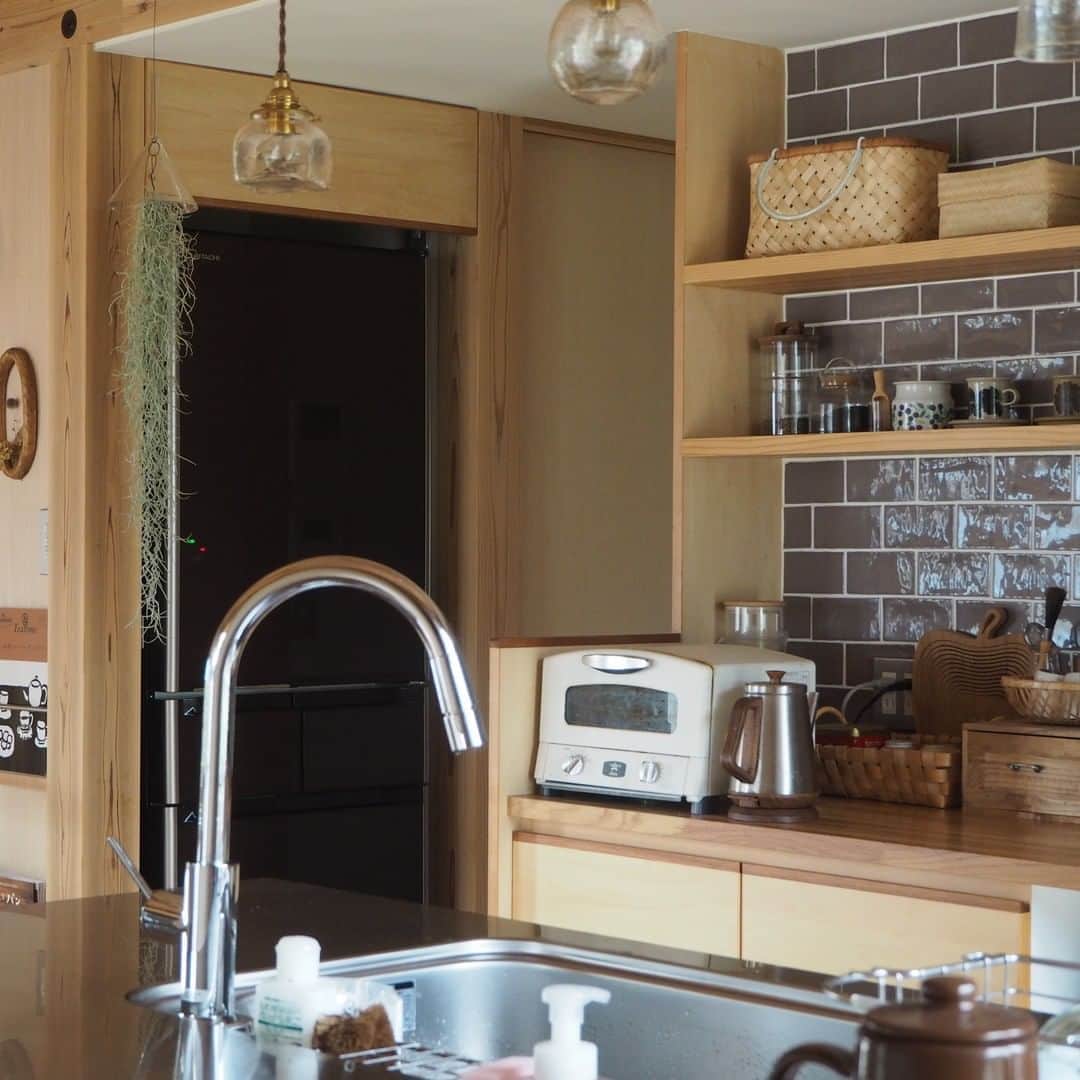 ムクリ［mukuri］さんのインスタグラム写真 - (ムクリ［mukuri］Instagram)「目を惹くキッチンは我が家の顔〜田舎町に溶けこむ風情のあるおうち（ayumi2519さん）  ブラウンのタイルと無垢材が パッと目を惹く温かみのある造作キッチン。  キッチンは家の中心的存在であり、 ayumiさんが一番好きな場所なんだそう。  毎日使うのはもちろん、 夢である石けん教室を開くことを思い描いたキッチンには ayumiさんの特別な思いが詰まっていました。  家の中で目を惹く存在にするにはどうしたらいいか、こだわり抜いて考えられた自分だけの造作キッチンは思い入れもひとしお。  息子さんとのほっこりするエピソードやアイランドキッチンの使い勝手についてもお話してくださっています。  ayumiさんのキッチンに込めた思い、 どうぞご覧ください♩  @ayumi2519 さん、ありがとうございました！ （編集:maki）  --------------------------------- ●キッチンシンク側 ・幅180×奥行き90×高さ85（センチ）  ●背面キッチン ・幅270×奥行き64×高さ86（センチ） ・天板材質：不明/鏡面塗装仕上げ  ●背面壁 ・タイル：リクシル/型番不明 ・飾り棚幅180×奥行き25.5（センチ） ・棚の間隔：25.5センチ ---------------------------------  ▶詳細はプロフィールのURLよりご覧ください プロフィールはこちらから @mukuri_official ・  #キッチンインテリア#造作キッチン#キッチン#キッチンタイル#キッチン収納 #アイランドキッチン#木の家#マイホーム#マイホーム計画#無垢材の床 #自然素材の家#ダイニングテーブ#古道具#古道具のある暮らし #アンティーク家具 #アンティークのある暮らし#暮らし#暮らしを楽しむ #暮らしの記録 #暮らしを整える #暮らしの道具 #日々の暮らし#緑のある暮らし #ナチュラルインテリア#北欧ナチュラル#くらしの編集#ムクリ」10月9日 21時05分 - mukuri_official