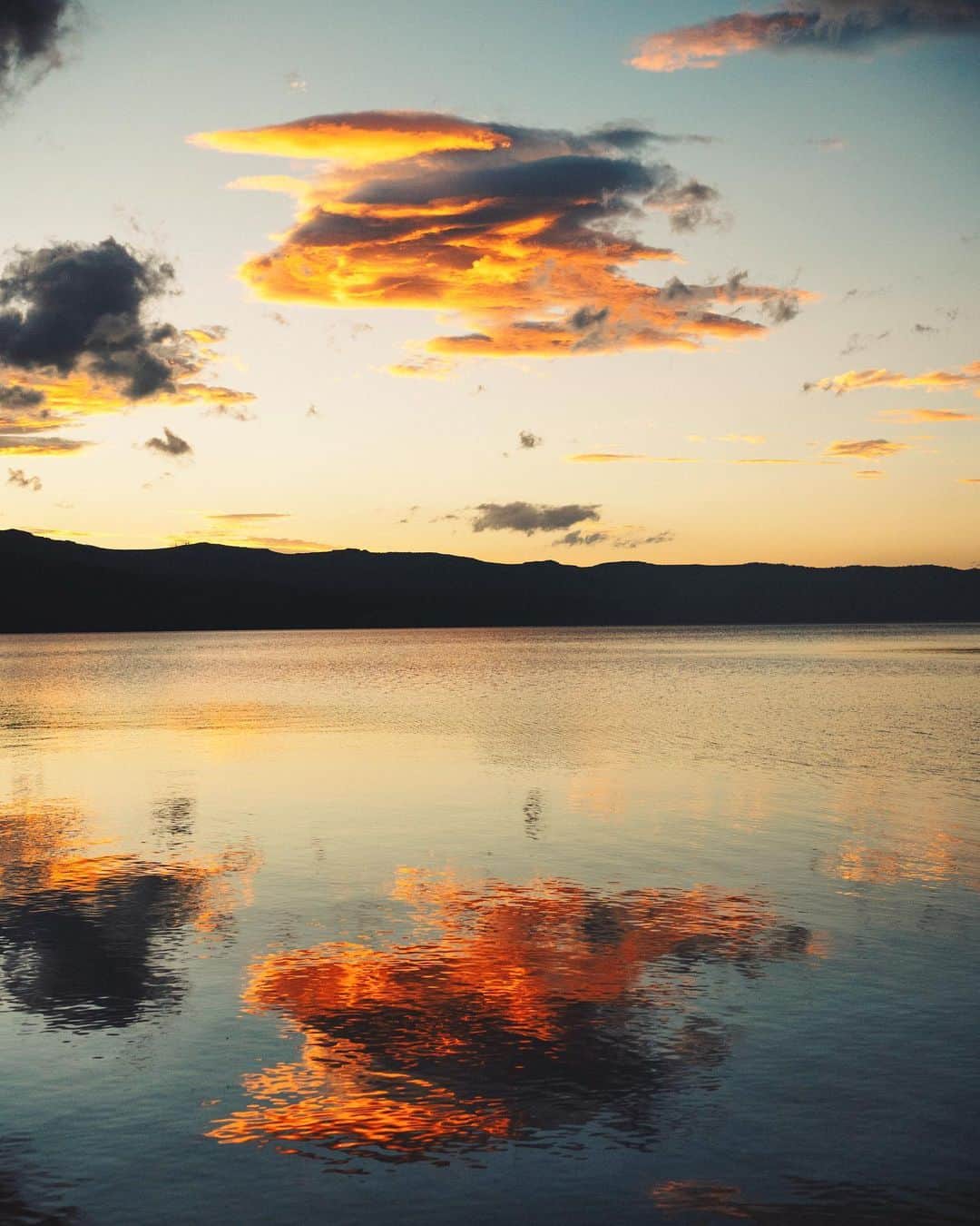 GENTAのインスタグラム：「☁️ 屈斜路湖の和琴半島は夕焼けの名所。 ここにはキャンプ場があり、湖畔にテント張ってくつろぎながら沈む夕陽を眺めることができます。  SONY の α Universe で僕の撮り下ろし作品と記事『純正が引き出すカメラの真価 ～増田元太氏×FE 35mm F1.8～』が公開されました。ストーリーズハイライトのリンクからご覧頂けます。 ㅤ #SEL35F18F #a7RIII #SonyAlpha #BeAlpha」