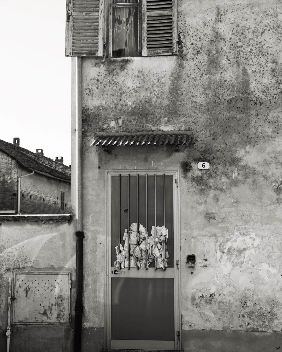 スコット・シューマンのインスタグラム：「A few years ago I spent some extra time in Italy before going to Pitti Uomo, for several days I would start driving around Tuscany at 6am and didn’t return until the sun was down. Some days the only person I spoke to was the bartender when I ordered my morning espresso! I was thinking about saving some of those images for a future book on Italy but i miss being there and I imagine a lot of you also miss traveling around Italy. What I love about this image is that although the place is obviously vacant someone just kept shoving flyers in between the doors hopeful that someday someone would return.」