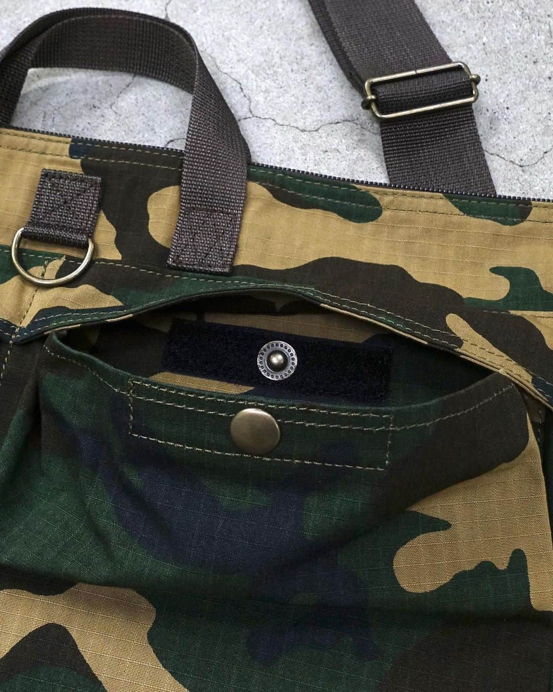 PORTER STANDさんのインスタグラム写真 - (PORTER STANDInstagram)「.﻿ SHOP ORIGINAL﻿ PLATOON﻿ ﻿ オリジナルで製作したコーデュラ®ナイロンとコットンのリップストップ生地に、カモフラージュ柄の中でも代表的なウッドランドパターンをプリントしたパッカブルシリーズ。﻿ ﻿ 2WAYヘルメットバッグはA4ファイルや雑誌が収納可能で、デイリーユースでお使いいただけます。外装・内装ともにポケットを設け、細かい荷物を整理するのに便利です。﻿ ﻿ 2WAY HELMET BAG﻿ No.381-16833﻿ ￥22,000+tax ﻿ W390/H410mm﻿ ﻿ #yoshidakaban #porter #luggagelabel #porterflagshipstore #madeinjapan #japan #porterstand #shinagawa #tokyo #kyoto #platoon #2way #helmetbag #military #woodlandcamo #packable #exclusive #吉田カバン #ポーター #ポータースタンド #品川 #東京 #京都 #プラトーン #ヘルメットバッグ #カモ柄 #ミリタリー」10月31日 15時18分 - porter_stand