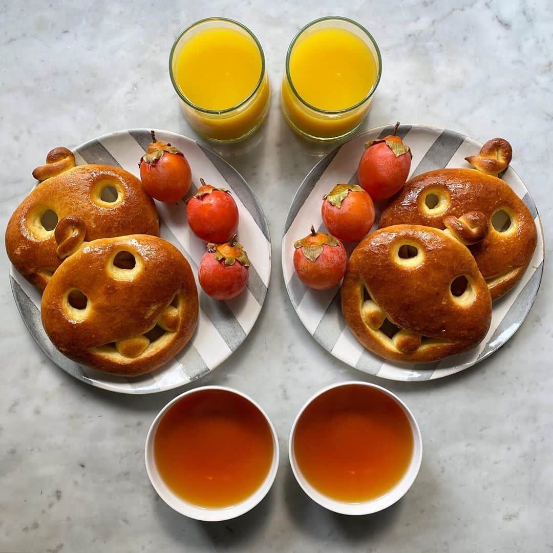 Symmetry Breakfastのインスタグラム：「Happy Halloween y’all 🎃! Cracking out the pumpkin faces again, quite simple really. cut out the mouth and stretch the dough, then use the piece you cut out for the eyes as teeth 😬 glazed with honey and served with seasonal persimmon from 陕西. Working those autumnal colours hard and matched with these striped plates from @skandihus_london that remind me of the film Beetlejuice 👻  - - - - - - - - - - - - - - - - - - - This is our fourth Halloween now in Shanghai, and I’m always so amazed how particular holidays have gone mainstream in this city and across China. I guess any excuse to dress up and have a party will do! 😂 #symmetrybreakfast」