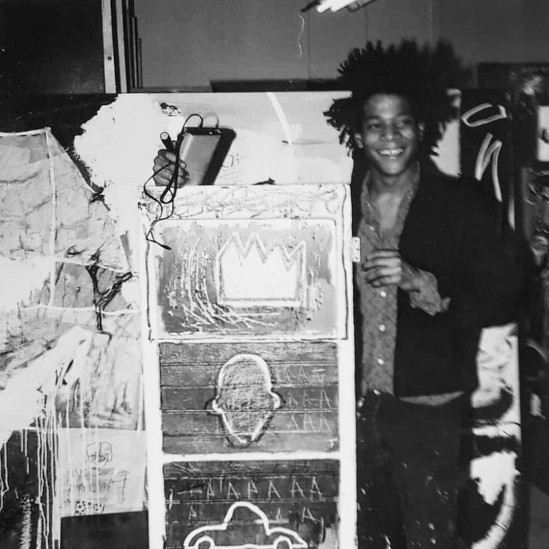 サザビーズさんのインスタグラム写真 - (サザビーズInstagram)「📸: Snapped here is Jean-Michel Basquiat side-by-side with his work ‘Minor Success’ at Annina Nosei Gallery in 1982. Dating to the very earliest phase in the artist’s career, the work was created two years prior and features three of what would become the artist’s most iconic motifs – 🚗 💀 👑 – drawn on the surface of a mirrored cupboard door.   1980 was a watershed moment for #Basquiat. Following his participation in ‘The Times Square Show’, the young artist was then invited to exhibit as part of the ‘New York / New Wave’ at @momaps1, asking a then teenage Basquiat, at that time listed under the name SAMO, to create a bold installation of some 20 paintings.    ‘Minor Success’ is currently on display in our #London galleries alongside the artist’s ‘Justcome Suit’ from 1983, both of which will be offered on Wednesday in #SothebysContemporary Art livestreamed auction.   Pulsating with urban rhythm, 👉 to see the frenetic ‘Justcome Suit’ composition swathed with a myriad of references that evoke the language of NYC in disarray.  © The Estate of Jean-Michel Basquiat / ADAGP, Paris and DACS, London 2020」10月17日 17時04分 - sothebys