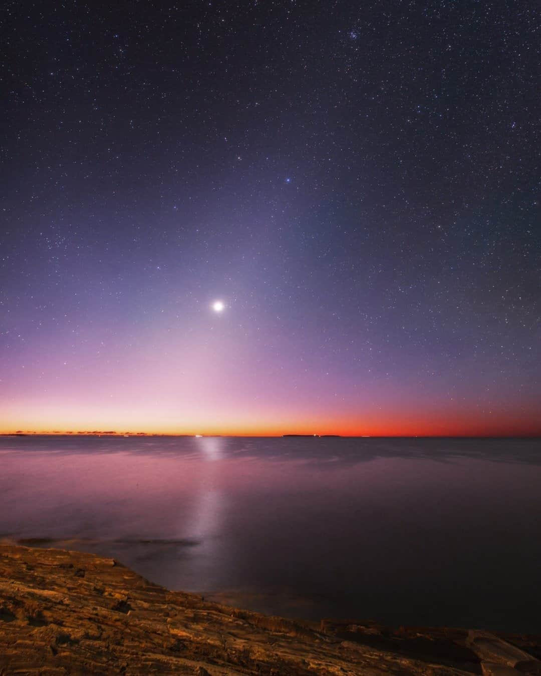 National Geographic Travelさんのインスタグラム写真 - (National Geographic TravelInstagram)「Photo by @babaktafreshi / Venus in ocean twilight glows before sunrise over the Atlantic coastline of Maine, New England. The cone-shaped glow of zodiacal light appears too, only visible far from light pollution in natural night sky. It's the sunlight reflecting from asteroid dust in the solar system.  Astronomers recently revealed a possible sign of life in the high clouds of Venus. The hostile planet with a surface temperature of 465°C (about 900°F) and crushing atmospheric pressure of 93 bar doesn't sound like a good place for life, but its high clouds can be home to aerial microbes. A rare molecule known as phosphine is found in the new radio observations of Venus clouds. On Earth it is produced by microbes in oxygen-free environments. Sample return missions are needed to confirm this, but it's certainly an exciting time for astronomy and space explorations.  Follow me @babaktafreshi for more Earth and sky wonders. #twanight #venus #life #maine」10月19日 3時36分 - natgeotravel