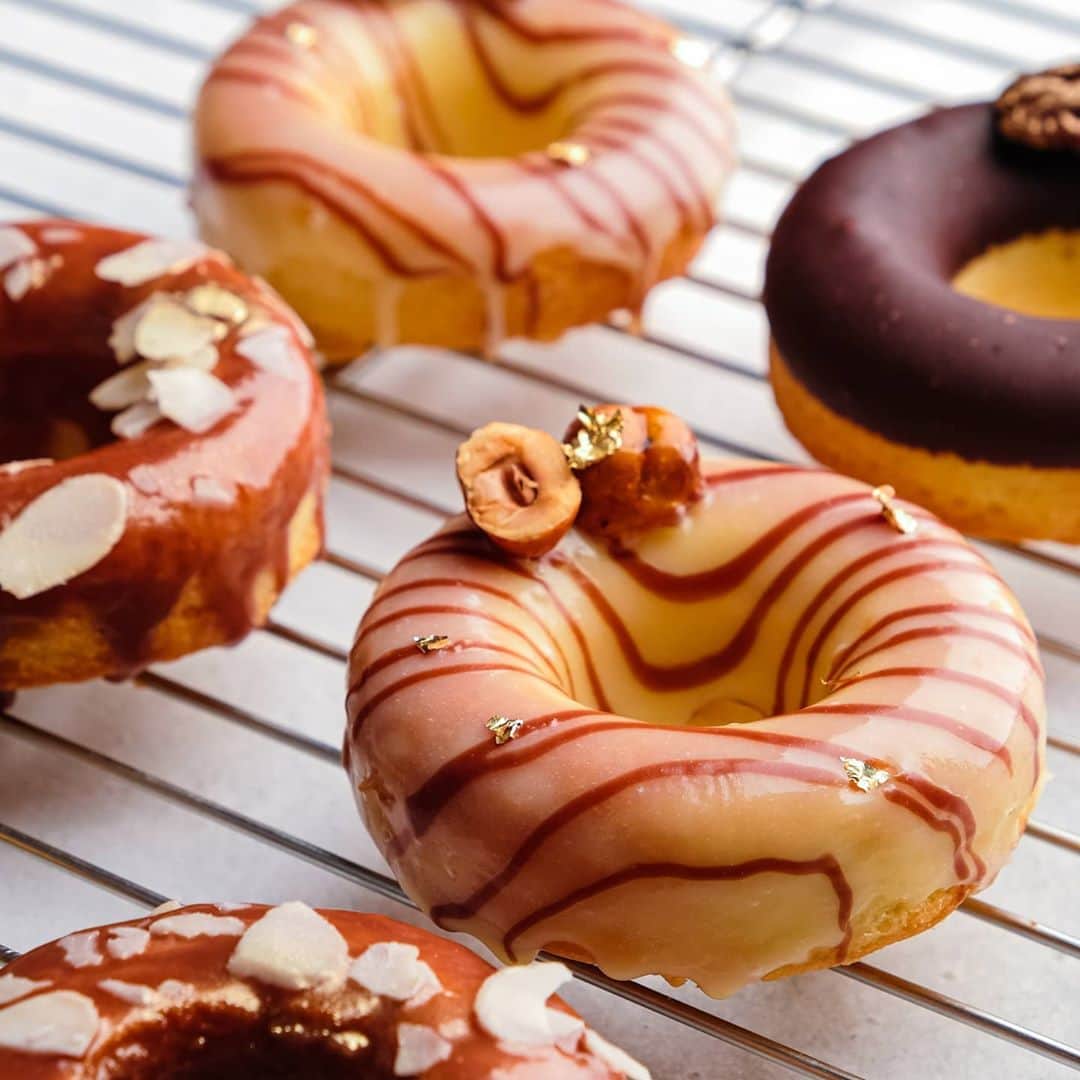 オリガ・ノスコワのインスタグラム：「Doughnuts can be a very special dessert if they are decorated festively. In this case, I used caramelized hazelnuts and gold flakes🌟 . Instead of frying these doughnuts, I baked them. This turned out to be a perfect replacement for a cake at a family dinner. . These doughnuts are actually very quick to make. I have filmed the entire process, which you will be able to see in my next post🙌. . Пончики могут стать особым десертом, если их празднично декорировать. Здесь я использовала карамелизованный фундук и золото🌟   Сами пончики не жарила, а выпекала. Получилась настоящая замена торту на семейном ужине.   И готовятся очень быстро. Засняла весь процесс и покажу в следующем посте🙌」