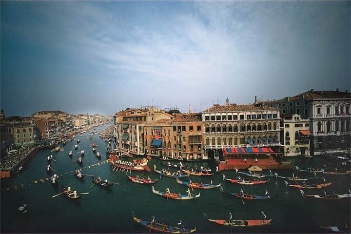 のインスタグラム：「Photo by @williamalbertallard / Venice, Italy, 1969. This is from my very first trip to Italy, where I made pictures of Venice for a National Geographic book. On the day of the most important regatta on the Grand Canal, I had arranged to photograph from the window of an apartment overlooking a sweeping curve in the canal. I used a Zeiss Hologon Ultrawide with a fixed 15 mm lens to capture this flowing procession of colorful gondolas, overlooked by observers on the balconies of the ancient stone and brick buildings. The image is reminiscent of a painting.   That camera was stolen from me later that year as I walked along a street in Saigon, grabbed from my hand by a youngster riding on one of the countless motor scooters buzzing through the streets of southern Vietnam. For more images of Venice and other assignments spanning a five-decade career, follow me @williamalbertallard. #venice #italy #canal #regatta #filmphotography」