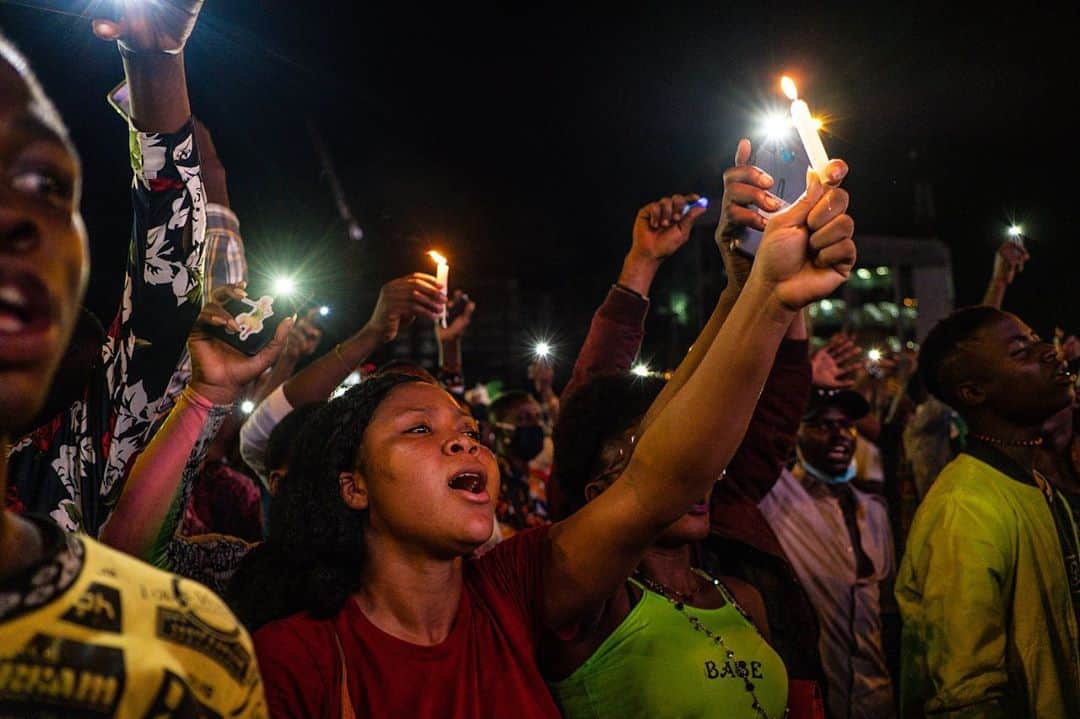 のインスタグラム：「Photos by Yagazie Emezi @yagazieemezi / These are scenes from peaceful protests at Lekki Toll Gate, in Lagos, one of many locations across Nigeria where youth have been making a stand against police brutality for two weeks. On October 20 around 7 p.m., security cameras were reported to have been removed from the toll gate and surrounding lights turned off, when the Nigerian military showed up and started shooting into the crowd. A number of protesters were injured and killed.  Earlier in the day, an impromptu 24-hour curfew had been announced, stating the move was an attempt to arrest “criminals and miscreants hiding under the umbrella of these protests.“  Protesters remained at the toll gate, singing the national anthem and waving green and white flags. As the shooting was underway, the curfew was extended to 9 p.m. via a tweet from state officials. The president has yet to make a public statement.  For more, follow @yagazieemezi.」