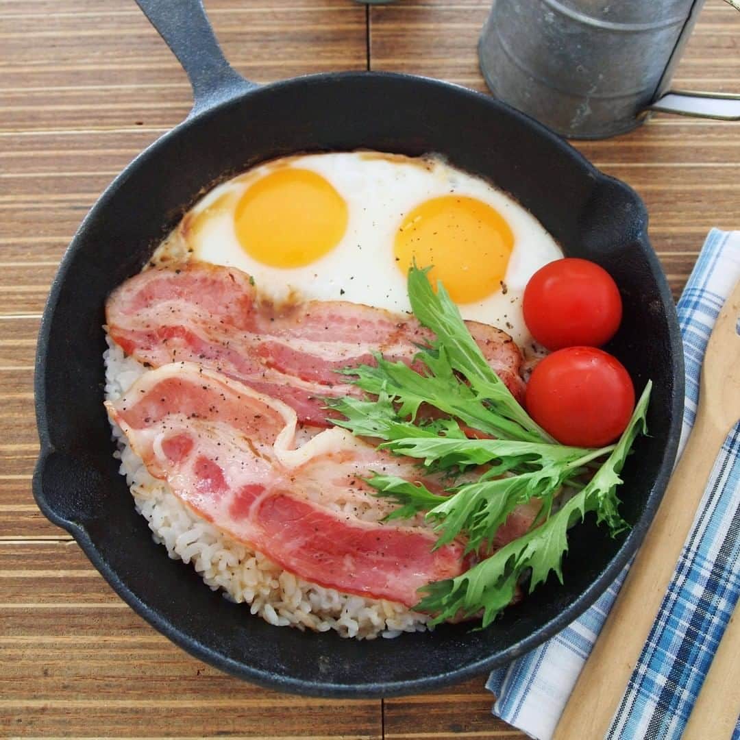 のインスタグラム：「【ベーコンエッグライス】 . 一皿でおいしいスキレットごはん。 アウトドアの朝食にもぴったり！ . ▼材料（１人分） ❁パックごはん：180g ×１パック ❁スライスベーコン（厚切り）：２枚（約50g） ❁卵：２個 ❁塩・こしょう：少々 ❁しょうゆ：小さじ１～ ［付け合わせ］ ❁ミニトマト：２個 ❁水菜：適量 . ▼作り方 ①スキレットでベーコンを軽く炒め、一度取り出しておく . ②同じスキレットにパックごはんをトレーからそのままほぐし入れ、軽く炒めて塩・こしょうする . ③ごはんを片側によせてベーコンをのせ、余白に卵を割り入れる . ④水（約大さじ１）をまわしかけ、専用のフタかアルミホイルでフタをする。 中弱火で約３分加熱する . ⑤卵が半熟になったら塩・こしょうをふり、全体にしょうゆをまわしかける . ⑥付け合わせの野菜をのせて召し上がれ . #ごはん #rice #gohan #パックごはん #パックご飯 #レシピ #おうちごはん #おうちキャンプ #庭キャンプ #簡単レシピ #キャンプ飯 #キャンプごはん #アウトドア飯 #アレンジレシピ #スキレット #ベーコンエッグ #デリスタグラム #foodstagram #今日のごはん #TableMark #テーブルマーク」