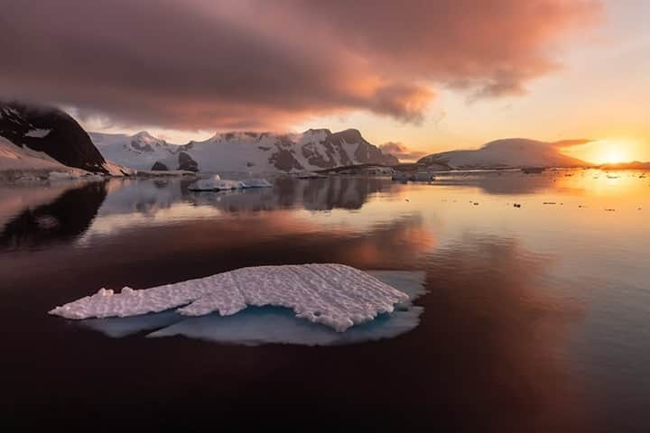 National Geographic Travelさんのインスタグラム写真 - (National Geographic TravelInstagram)「Photo by @daisygilardini / The warm colors of an Antarctic sunrise illuminate this scene. A strong foreground is essential to any successful landscape photograph. We look at things three-dimensionally with our own eyes in real life, but what we see through photography is flattened into a two-dimensional image. In order to enhance depth perception and lend an illusion of a three-dimensional space, one needs a strong foreground to lead the viewer’s eye into the image. In this particular instance, I chose to use the iceberg in the foreground. I took extra advantage of the iceberg’s complementary colors in order to lead the eye into the beautiful sunrise reflection and ice field in the background. Follow me @DaisyGilardini for more images and stories behind the scenes. #Antarctica #iceberg #sunrise #landscapephotography #polar」10月25日 7時35分 - natgeotravel