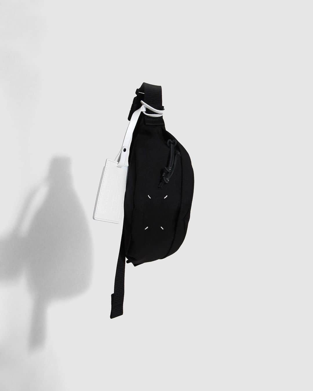 A+Sのインスタグラム：「in stock now   ■Maison Margiela 4-STITCH BUM BAG COLOR : BLACK SIZE : W 29㎝ ×D 9㎝ ×H 12㎝  PRICE : ¥59,000 (+TAX)  ※こちらの商品は実店舗＆お電話での通信販売のみとなります。お求めの際はお気軽にお問い合わせ下さい。  クロスボディスタイルのキャンバス製バッグです。フロントにメゾンを象徴する4本ステッチのディテールがあしらわれ、コントラストを効かせたレザータブを備えています。プルタブ付きのファスナー開閉式で、バックで調節可能なストラップが配されています。 イタリア製。   A cross-body style canvas bag. The front features four stitching details that symbolize the Maison and features contrasting leather tabs. It has a zipper closure with a pull tab and an adjustable back strap. made in Italy.  #a_and_s #MaisonMargiela #MaisonMargielaBUMBAG #MaisonMargiela4STITCHBUMBAG @maisonmargiela」