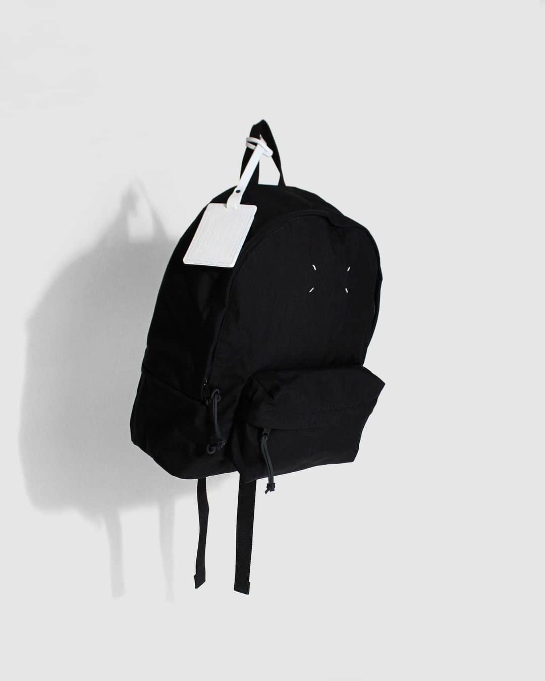 A+Sのインスタグラム：「in stock now  ■Maison Margiela ZAINO PICCOLO STEREO COLOR : BLACK SIZE : W 33㎝ ×D 17㎝ ×H 43㎝  PRICE : ¥98,000 (+TAX)  ※こちらの商品は実店舗＆お電話での通信販売のみとなります。お求めの際はお気軽にお問い合わせ下さい。  素材感に特徴のあるナイロンを使用したバックパックです。Maison Margielaのコントラストを生み出すステッチがフロントを飾り、STEREOTYPEラベルをデボス加工した取り外し可能なレザータグが付いています。フロントにファスナーポケットが付き、レザー製のファスナープルが付いたフロントのダブルファスナーで開閉します。 イタリア製。  A backpack made of nylon, which has a distinctive texture. Maison Margiela's contrasting stitching decorates the front and features a removable leather tag with a debossed STEREOTYPE label. It has a zipper pocket on the front and a double zipper on the front with a leather zipper pull that opens and closes. made in Italy.  #a_and_s #MaisonMargiela #MaisonMargielaBackPack #MaisonMargielaZAINOPICCOLOSTEREO @maisonmargiela」