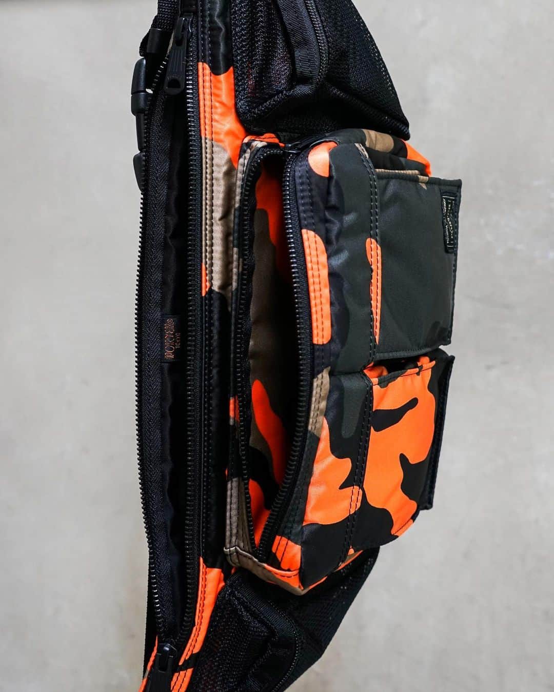 のインスタグラム：「.﻿ SHOP ORIGINAL﻿ PS CAMO﻿ ﻿ ウッドランドパターンのカモフラージュ柄に、ビビットなオレンジカラーを取り入れたPORTER STANDオリジナルシリーズ。﻿ ﻿ 薄マチでありながら、細かな収納ポケットを多数装備した機能性の高さも特徴です。﻿ ﻿ WAIST BAG﻿ No.384-05757﻿ ￥20,000+tax﻿ W480/H170mm﻿ ﻿ #yoshidakaban #porter #luggagelabel #madeinjapan #japan #porterstand #shinagawa #tokyo #kyoto #ps #camo #waistbag #limited #exclusive #吉田カバン #ポーター #ポータースタンド #品川 #東京 #京都 #限定 #ウエストバッグ」