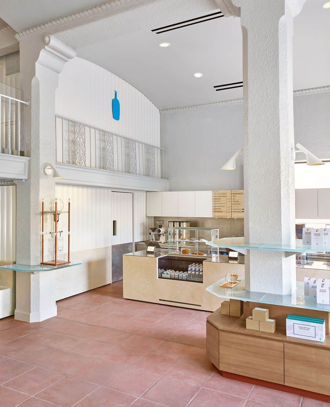 Blue Bottle Coffeeさんのインスタグラム写真 - (Blue Bottle CoffeeInstagram)「At our new Chapman Court Cafe in the heart of Los Angeles’ Koreatown, the past commingles with the present in beautiful ways. ⁠ ⁠ The historic building opened in 1929, designed by Morgan, Walls & Clements, the architectural firm known for its devotion to Spanish Revival–style design. The exterior is almost castle-like with thick concrete walls fashioned to resemble sandstone and decorated with ornate detailing some architecture buffs call Churrigueresque, referencing a style of ornamentation popular in 17th-century Spain. ⁠ ⁠ But stuck in the past our cafe is not. It revels in the historic elements, integrating the existing wrought-iron balconies and fluted wall panels into the two-story space. The amber-toned Botticino Semiclassico marble from Italy is our ode to the classic, while the sleek warmth of furniture made of walnut wood anchors us to the here and now.  Architecture by @wrk_shp. 📸 @yoshihiromakino」11月21日 2時39分 - bluebottle