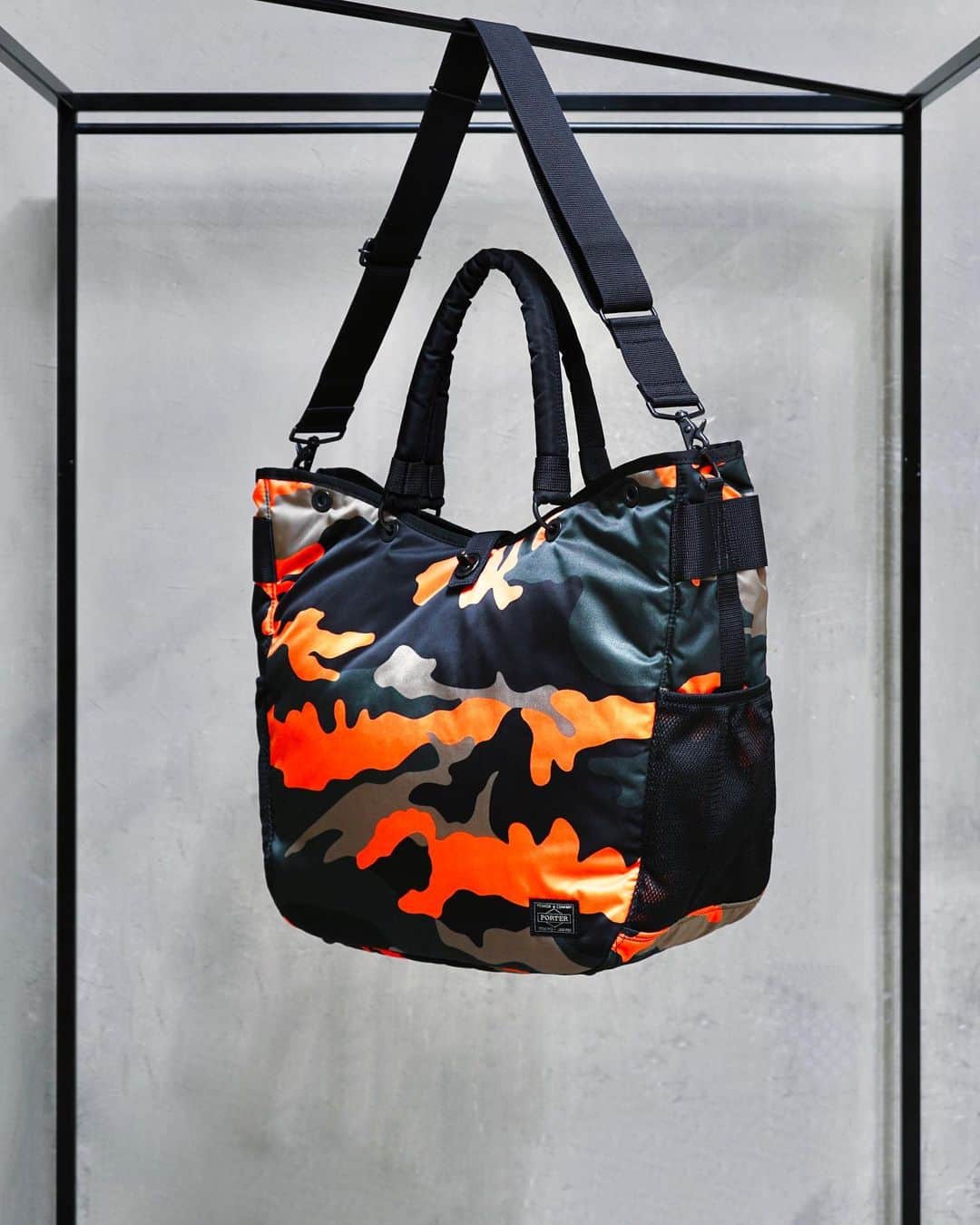 のインスタグラム：「.﻿ SHOP ORIGINAL﻿ PS CAMO﻿ ﻿ ウッドランドパターンのカモフラージュ柄に、ビビットなオレンジカラーを取り入れたPORTER STANDオリジナルシリーズ。﻿ ﻿ サイドに設けたペットボトルや折り畳み傘が収納可能なメッシュポケットや内装のPC専用ポケットなど充実した収納が特徴です。﻿ ﻿ 2WAY TOTE BAG﻿ No.384-08300﻿ ￥29,500+tax﻿ W350/H370/D180mm﻿ ﻿ #yoshidakaban #porter #luggagelabel #madeinjapan #japan #porterstand #shinagawa #tokyo #kyoto #ps #camo #totebag #limited #exclusive #吉田カバン#ポーター #ポータースタンド #品川 #東京 #京都 #カモフラージュ #トートバッグ」