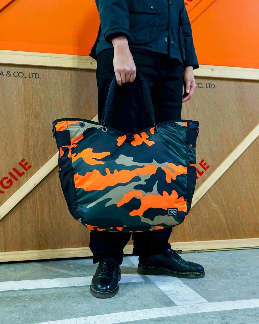 のインスタグラム：「.﻿ SHOP ORIGINAL﻿ PS CAMO﻿ ﻿ ウッドランドパターンのカモフラージュ柄に、ビビットなオレンジカラーを取り入れたPORTER STANDオリジナルシリーズ。﻿ ﻿ サイドに設けたペットボトルや折り畳み傘が収納可能なメッシュポケットや内装のPC専用ポケットなど充実した収納が特徴です。﻿ ﻿ 2WAY TOTE BAG﻿ No.384-08300﻿ ￥29,500+tax﻿ W350/H370/D180mm﻿ ﻿ #yoshidakaban #porter #luggagelabel #madeinjapan #japan #porterstand #shinagawa #tokyo #kyoto #ps #camo #totebag #limited #exclusive #吉田カバン#ポーター #ポータースタンド #品川 #東京 #京都 #カモフラージュ #トートバッグ」