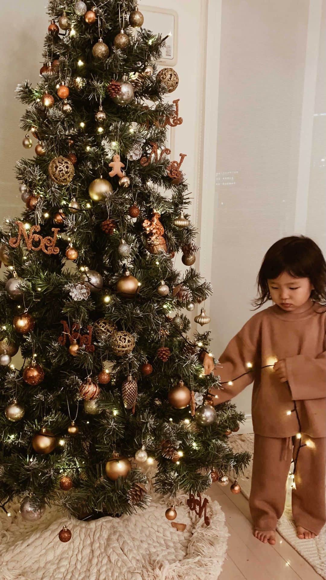 村上萌のインスタグラム：「今年のツリーのテーマカラーはブロンズにした。リビングに出してから1週間。100cm以下のところに飾ったクッキーオーナメントは全部かじられてる…🤦‍♀️   #娘まもなく100cm #今日を綴る #かぞくごと」