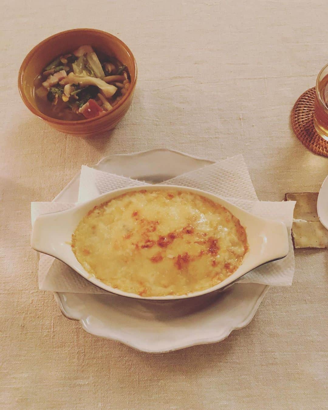 のインスタグラム：「私はほんとうにグラタンが好きだ。そもそもベシャメルソース自体が好きなんだと思う。  ベシャメルが好きなものだから、当然カニクリームコロッケも大好きなんだけど、あれを食べるたびに『なんという実態のない食べ物なんだ！でも美味しいっていったい…』と訝しがっている。  フンギポルチーニと和栗の炊き込みごはんドリア。昨夜のスープの残りに、レッドレンティル、ストック煮ベーコン、春菊を足した野菜スープ。  仕事が早めに終わって、ちょっとホッとする日曜日の夜。ピガ兄は、ぐっすり眠っていても、私が食卓へつくと起き出してつきあってくれる。  なんて優しいの。ごはんをひとりで食べるのは、決して楽しいことじゃないけど、キミの思いやりのおかげで、毎日楽しく頂けているよ。  #猫沢飯　#ピガ兄」